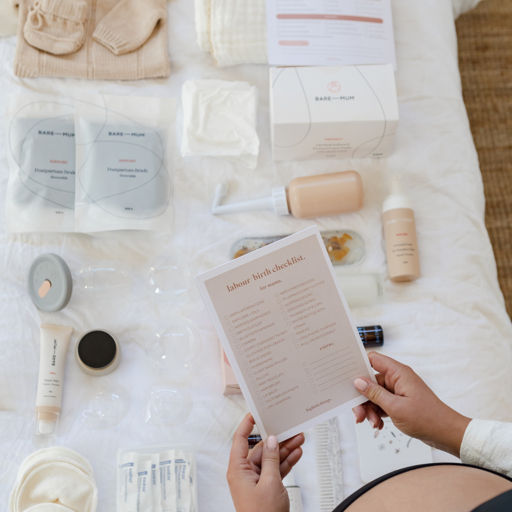 Birth and Postpartum care products sitting on a bed ready to packed for hospital using biglittlethings checklists.