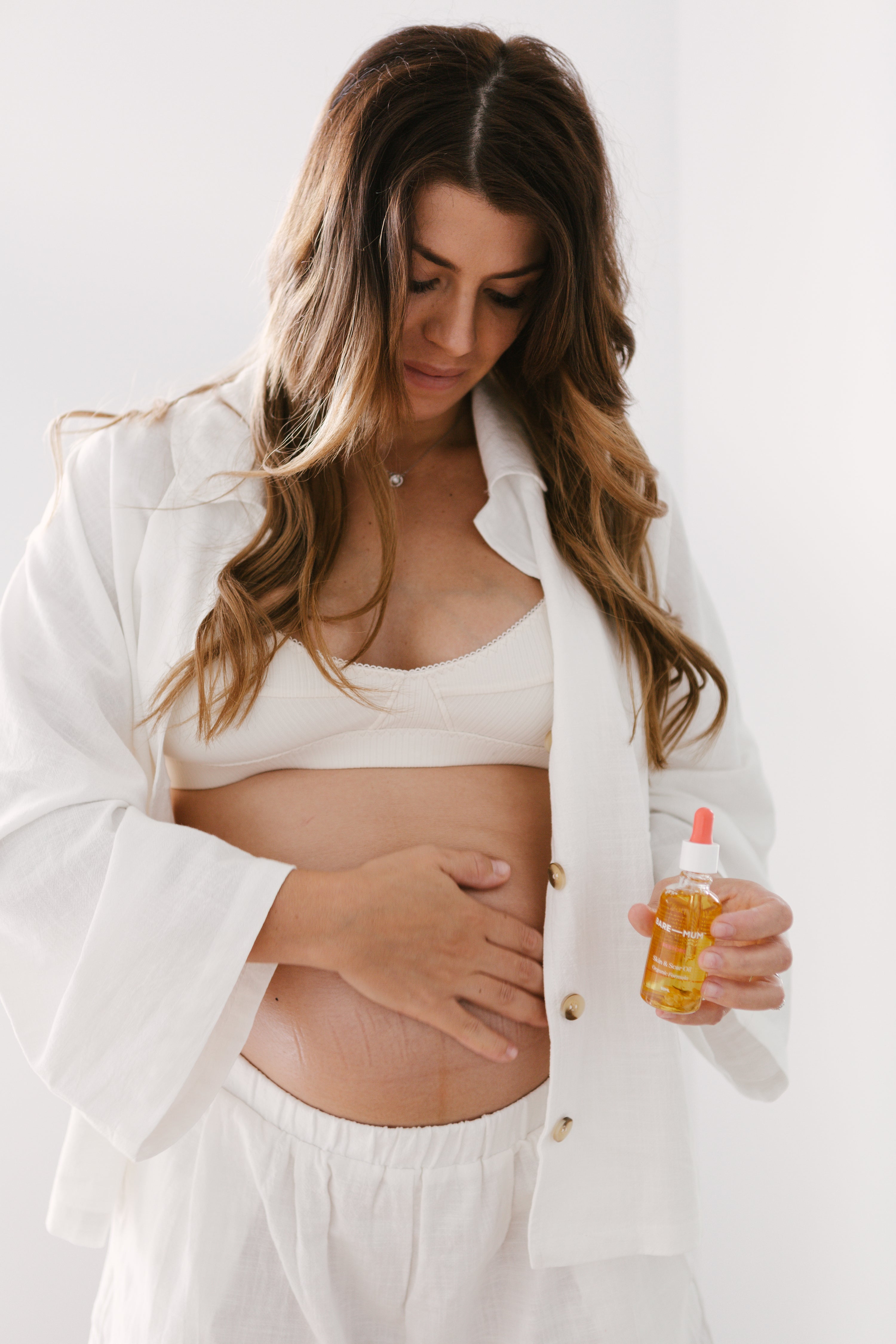 A pregnant woman holding a bottle of oil.