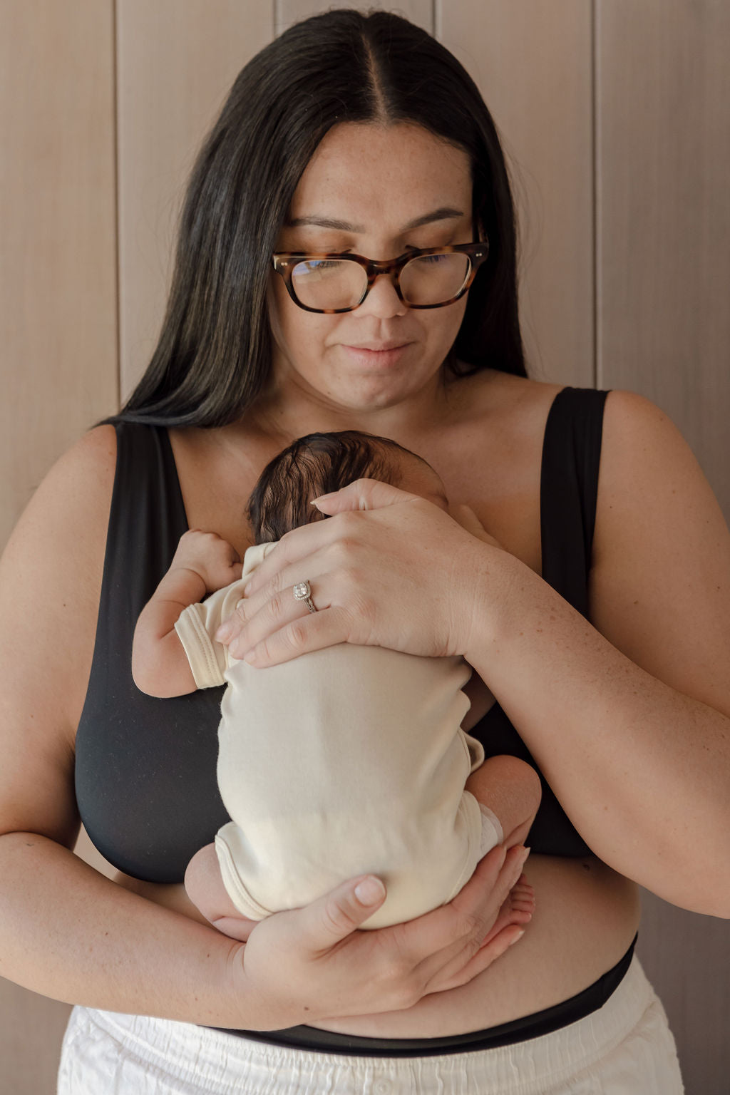 A woman holding a baby while wearing glasses.