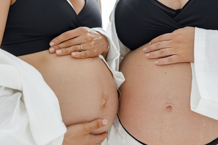 pregnant mothers holding their growing bellies as they wait for their babies and prepare for birth