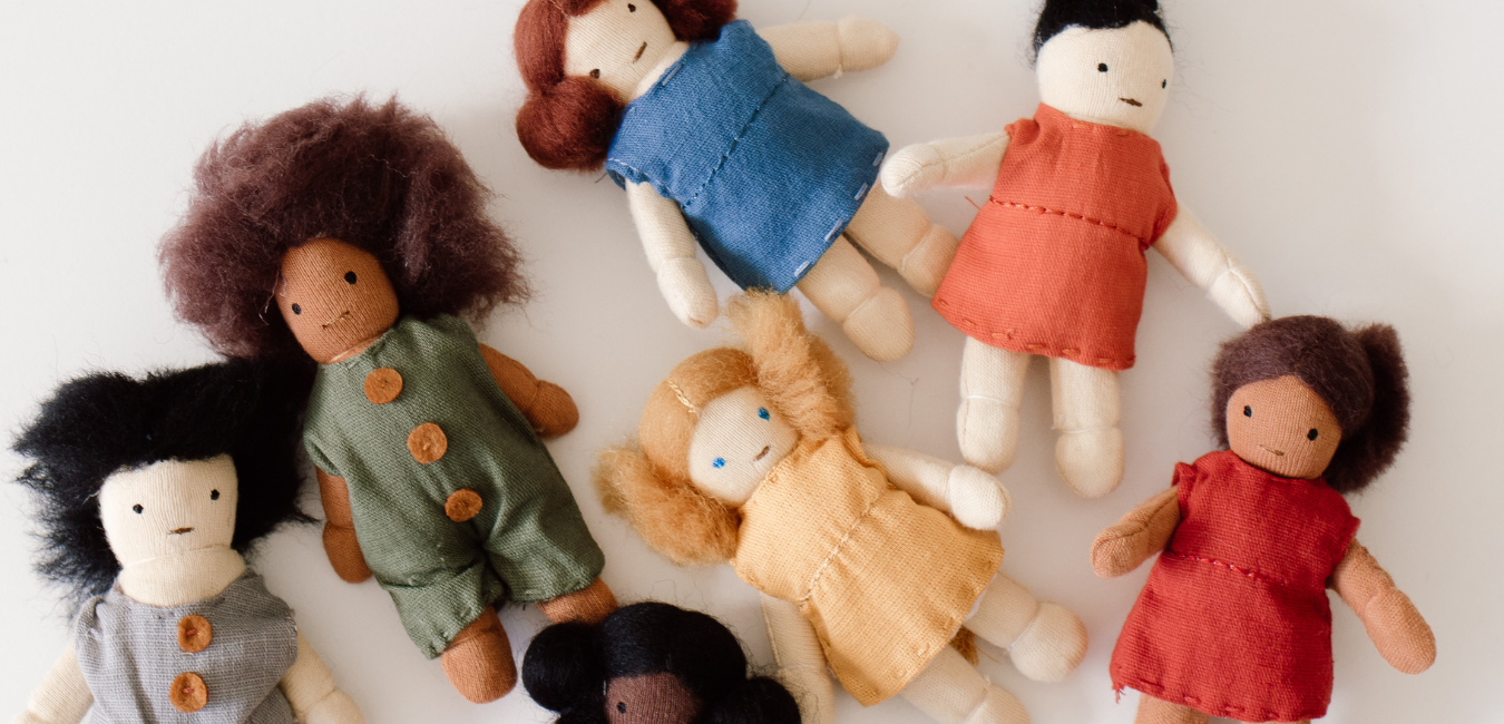 A group of dolls in different colors laying on a white surface.