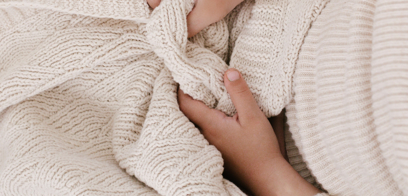 A woman's hands are wrapped up in a blanket.