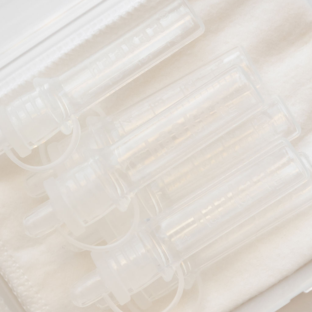 Four Haakaa Pre-sterilised Silicone Colostrum Collectors | 6pk sitting on top of a white cloth.