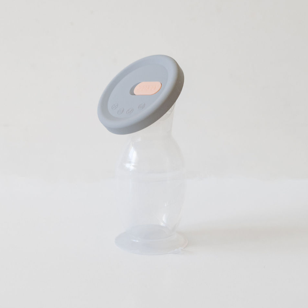 A small Haakaa Silicone Breast Pump & Silicone Cap | Gen 2 bottle with a lid sitting on a white surface.