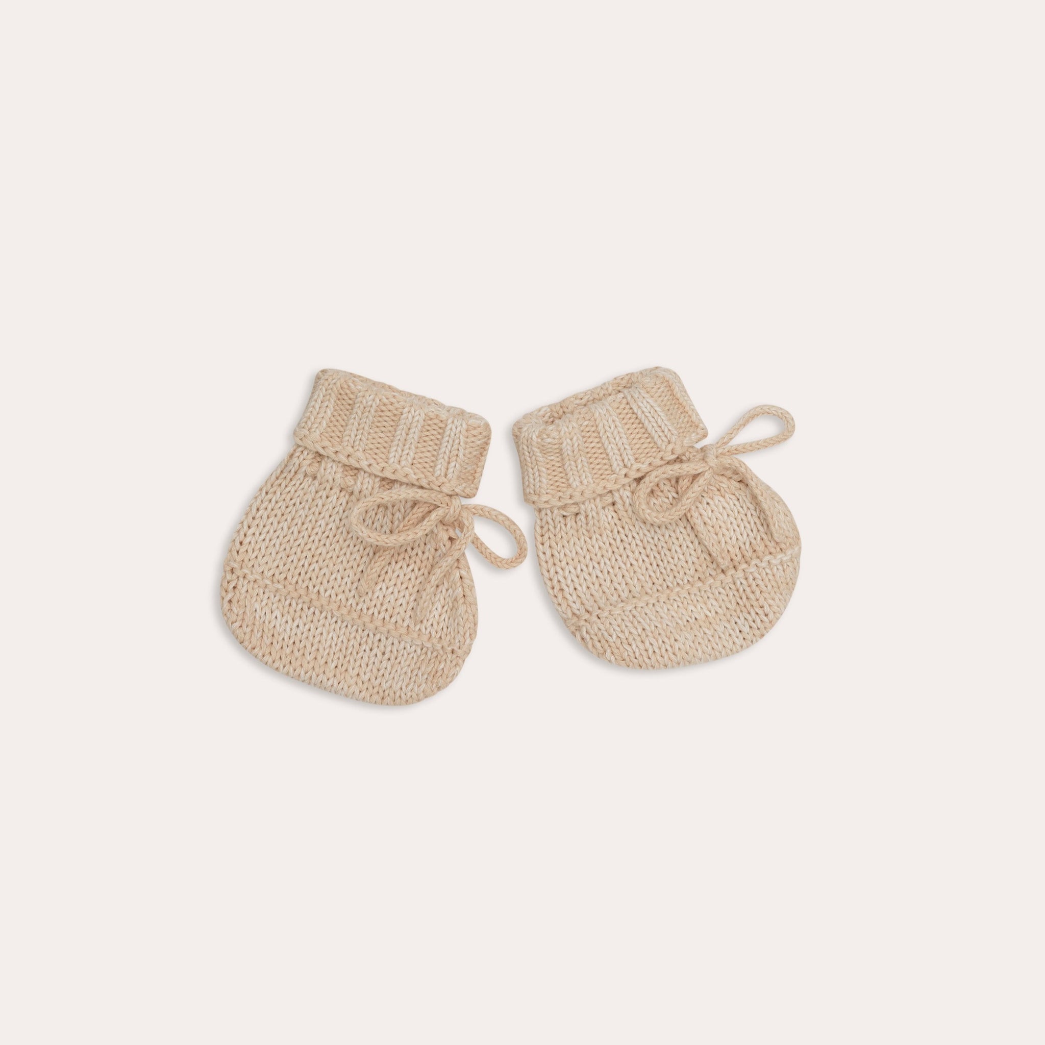 A pair of Illoura the Label knitted alba booties in sand on a white background.