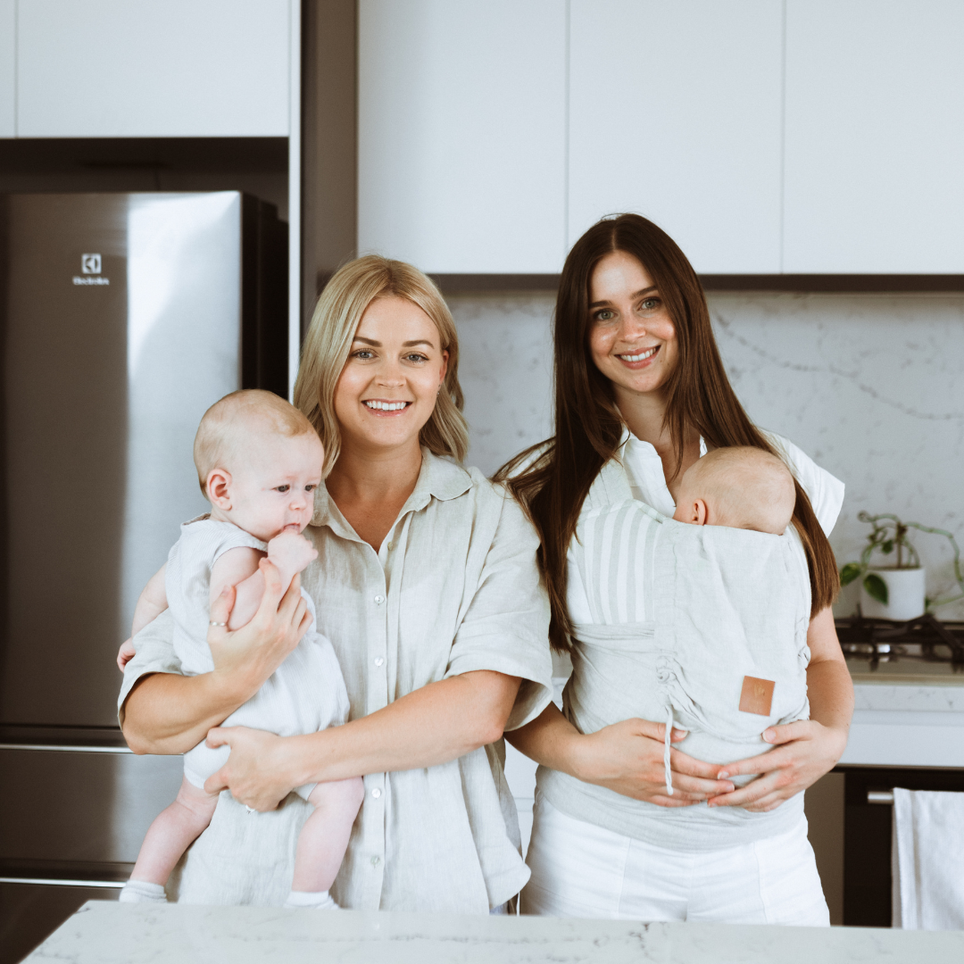 Three women holding babies in a kitchen with Nourished Postpartum from Mothers Mylk.