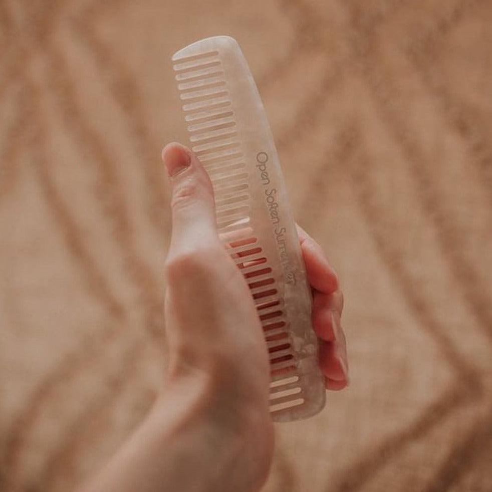 A person holding Seasons of Mama Birth wooden comb.