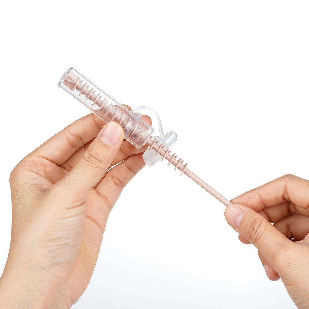 A person holding a plastic syringe on a white background, Haakaa Silicone Cleaning Brush Kit.
