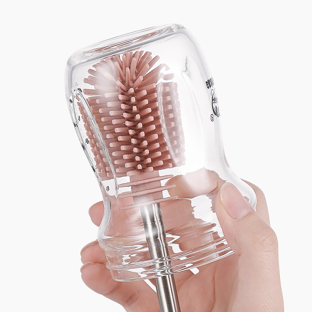 A person holding a glass cup with a Haakaa Silicone Cleaning Brush Kit from Haakaa.