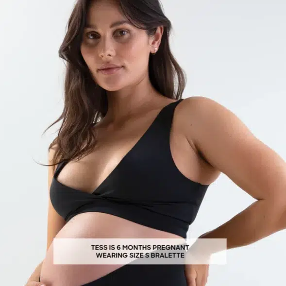 An image of a pregnant lady wearing a Postpartum Bralette by Bare Mum holding a baby.