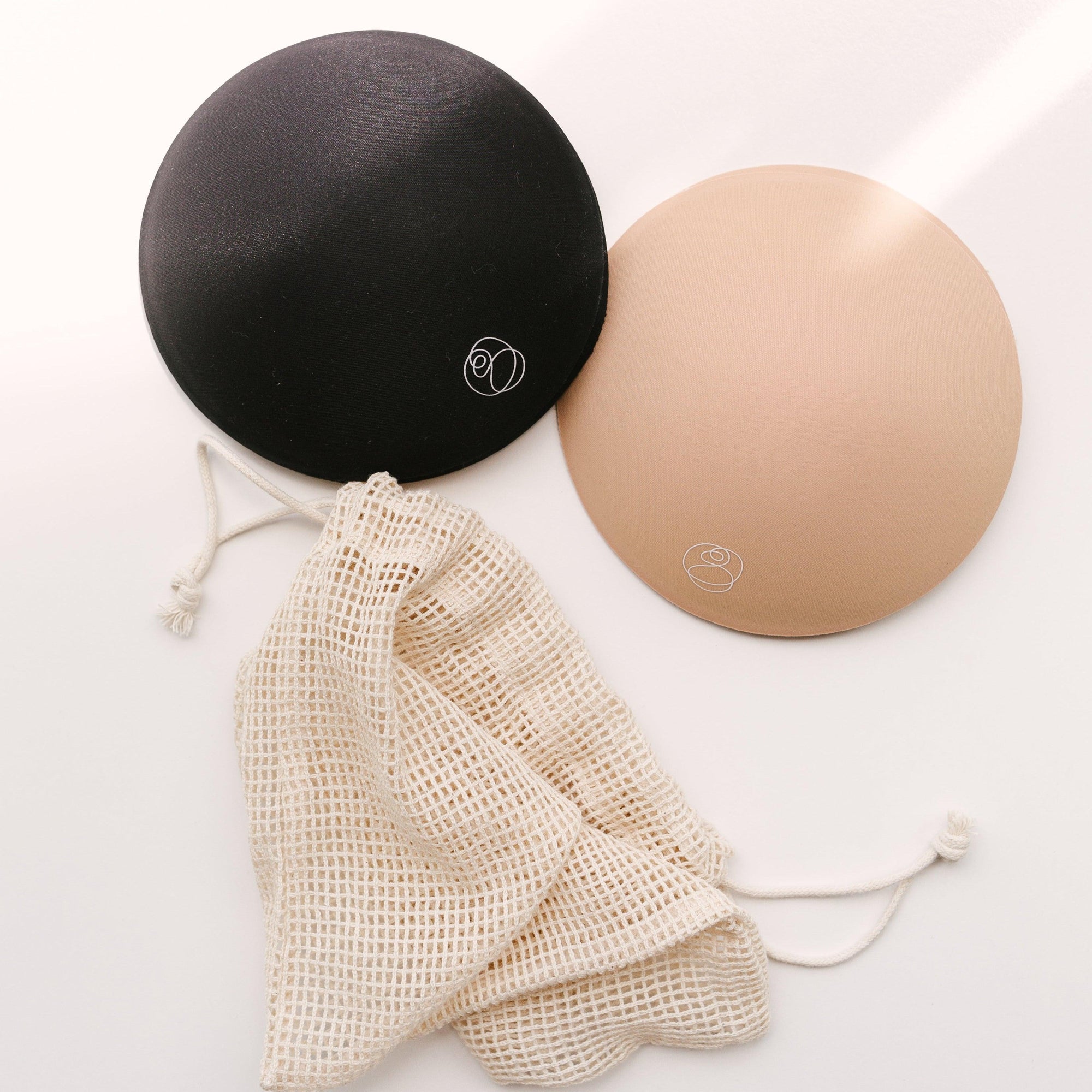 A pair of Bare Mum breast pads and a bag on a white surface.