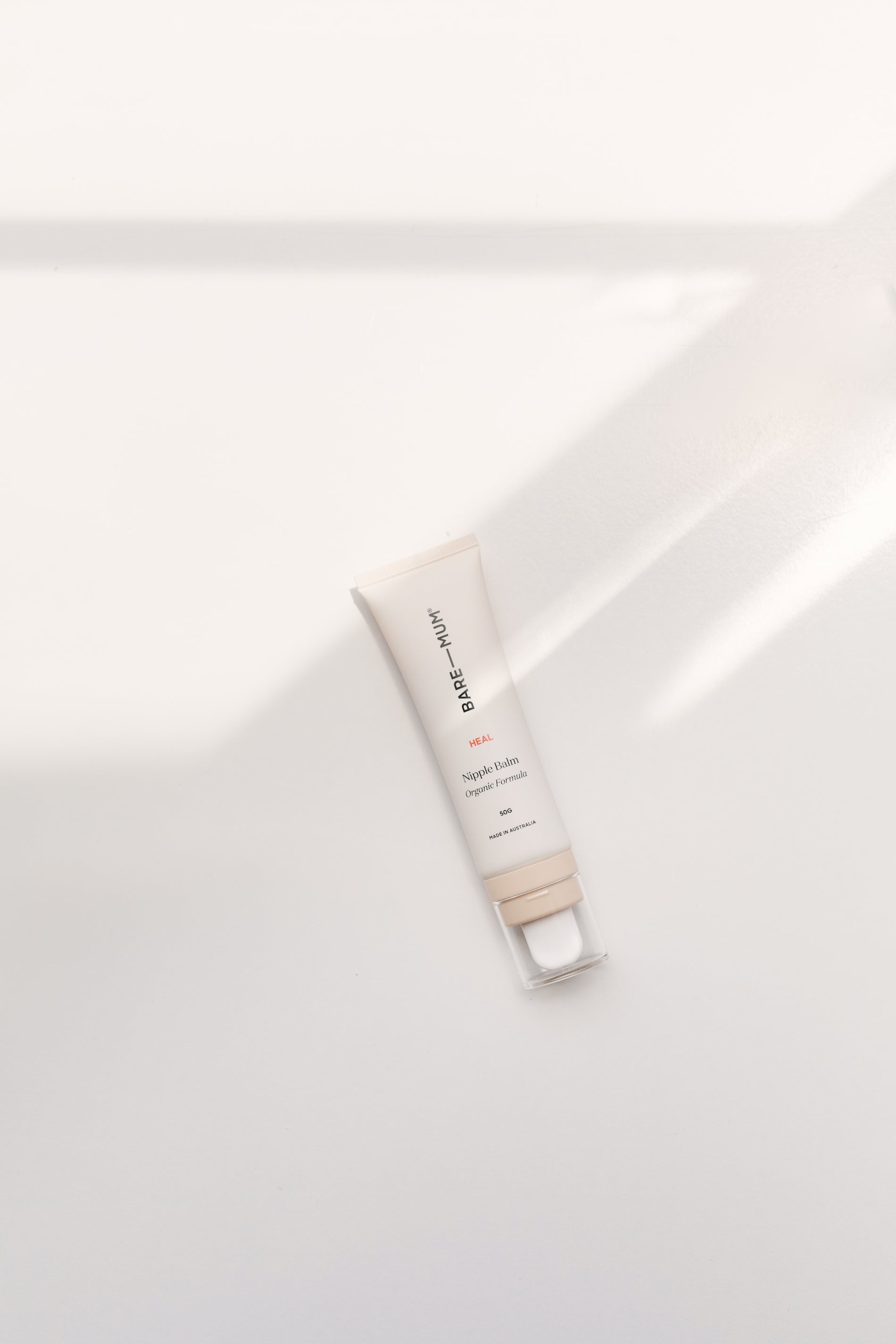 A tube of Bare Mum Nipple Balm sitting on a white surface, dedicated to mothers and breastfeeding.