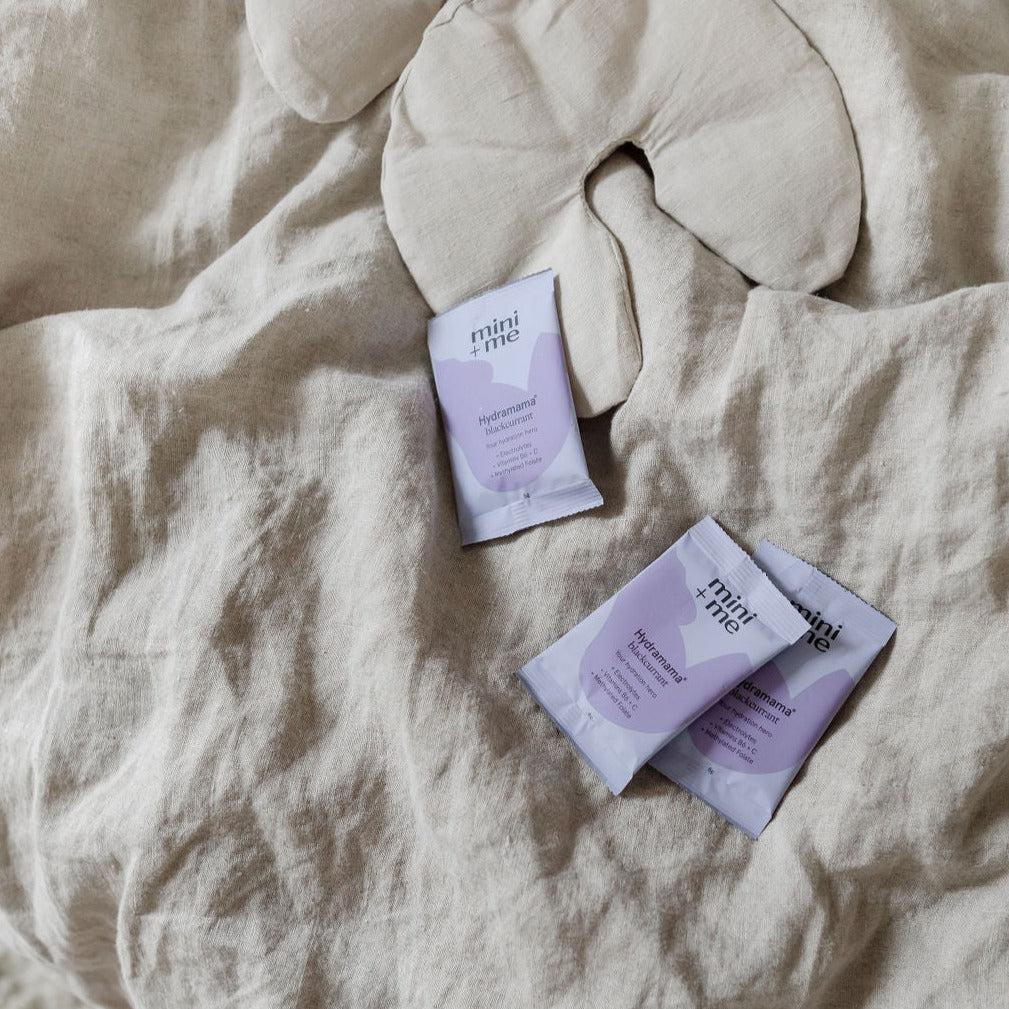Three packets of Mini+Me Hydramama® Blackcurrant sitting on a bed.