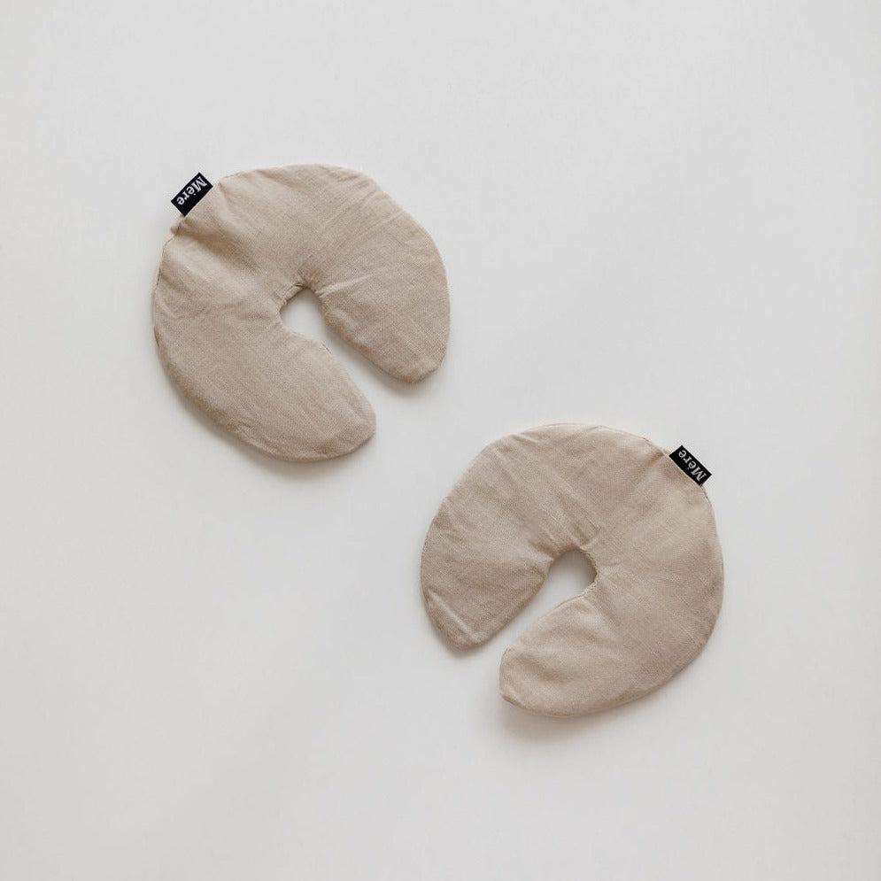 Two Breast Heat Packs by Mère on a white surface.