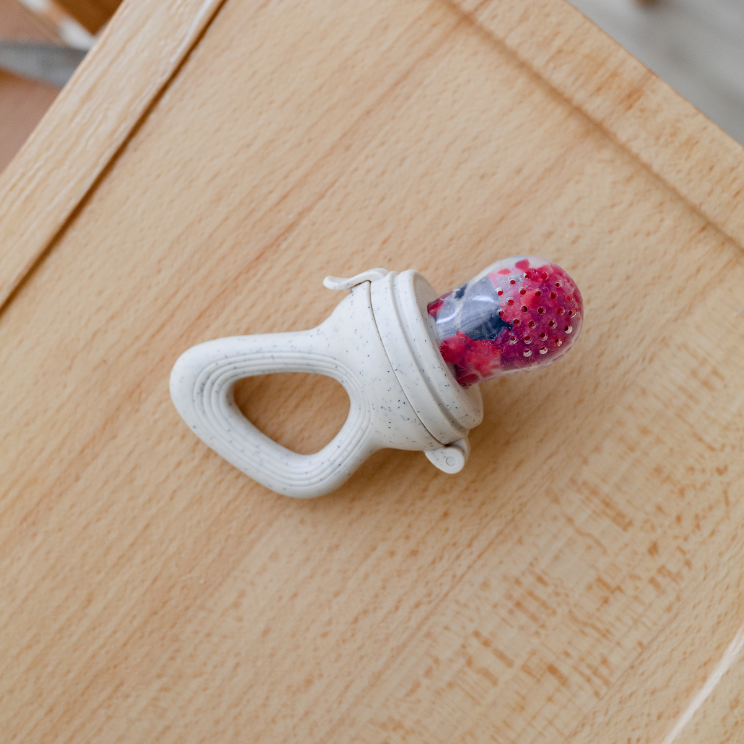 A Dove & Dovelet silicone self feeder with raspberries and blueberries in the feeder.