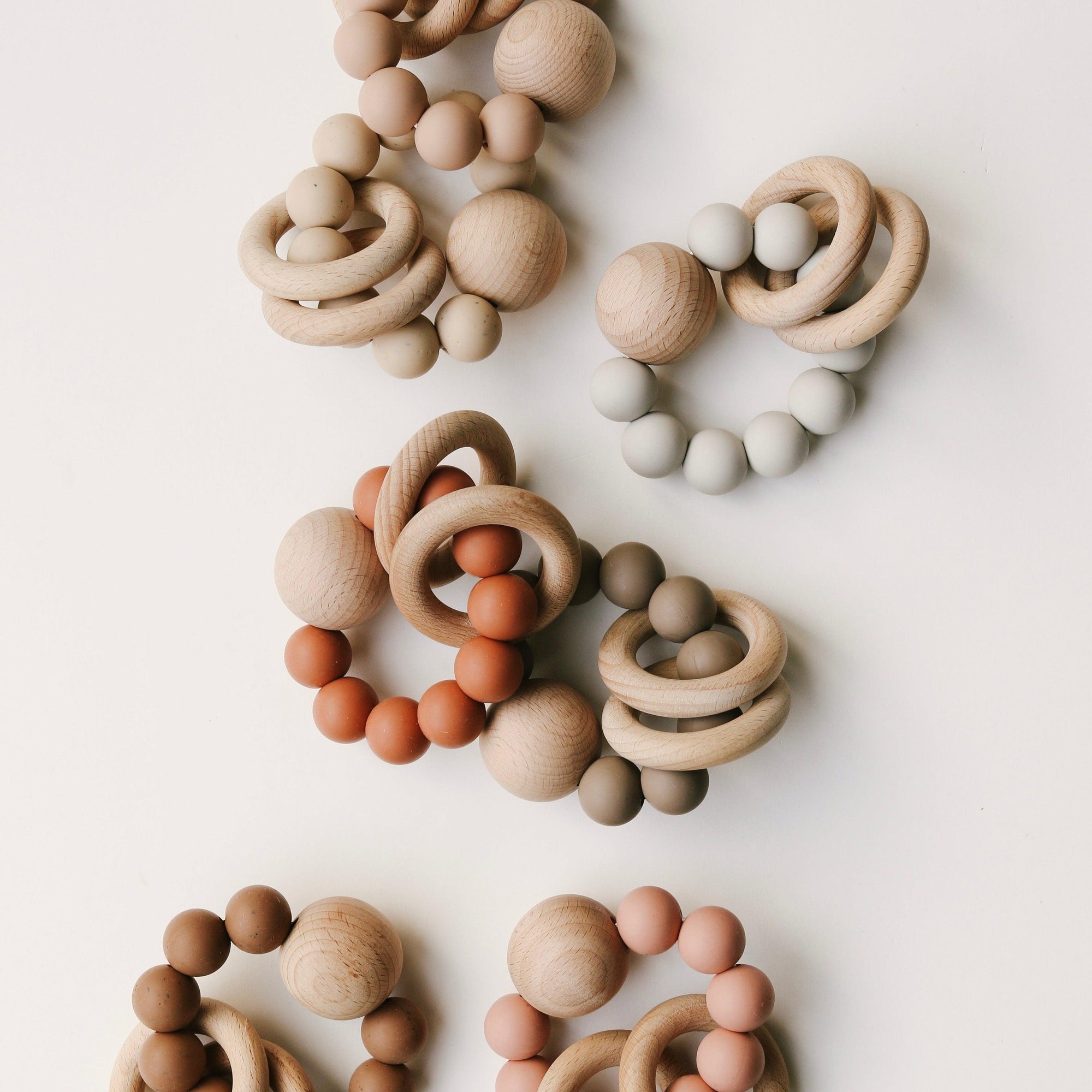 A group of Dove & Dovelet Wooden Silicone Teethers arranged on a white surface.