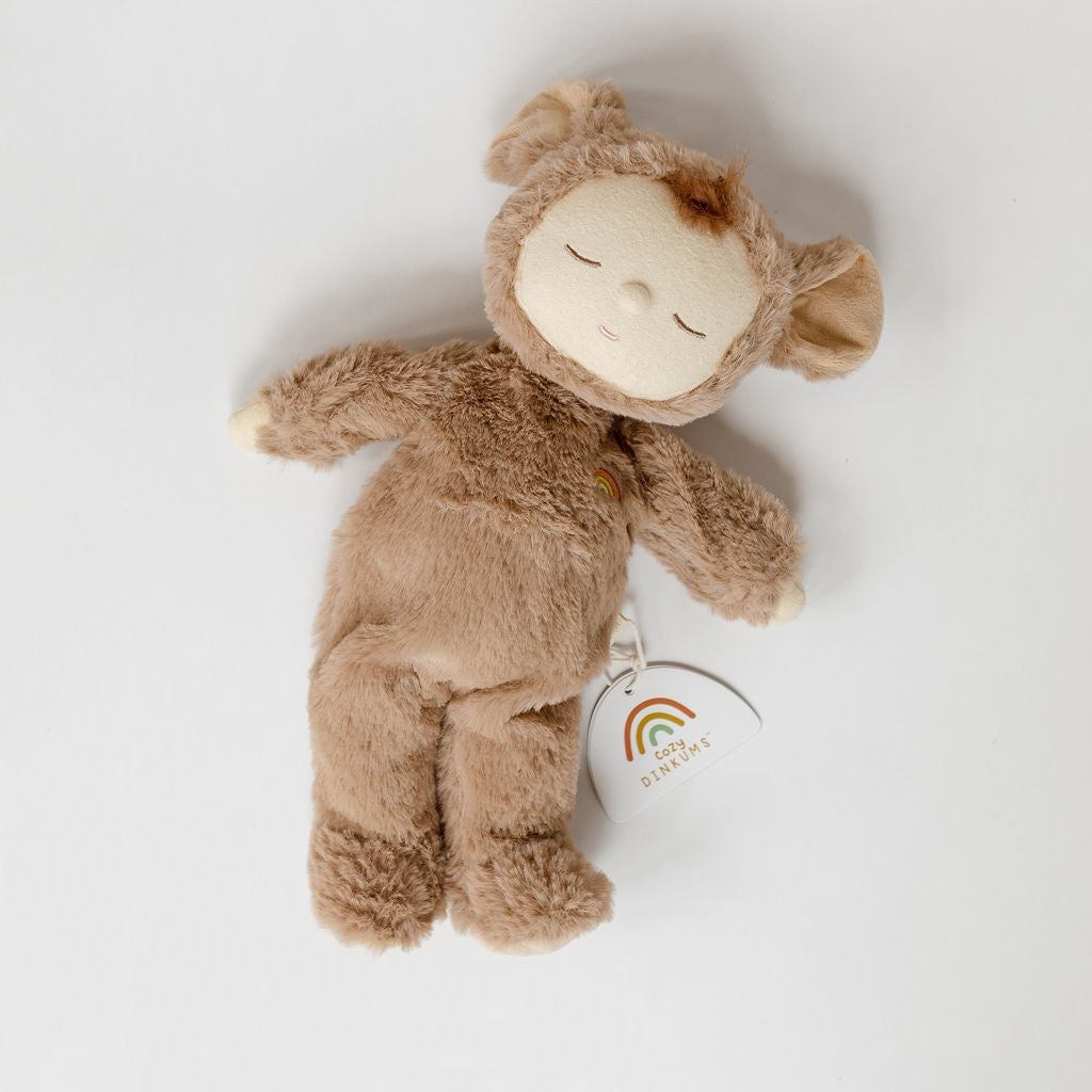 A cozy dinkums stuffed animal laying on a white surface. (Olli Ella brand)