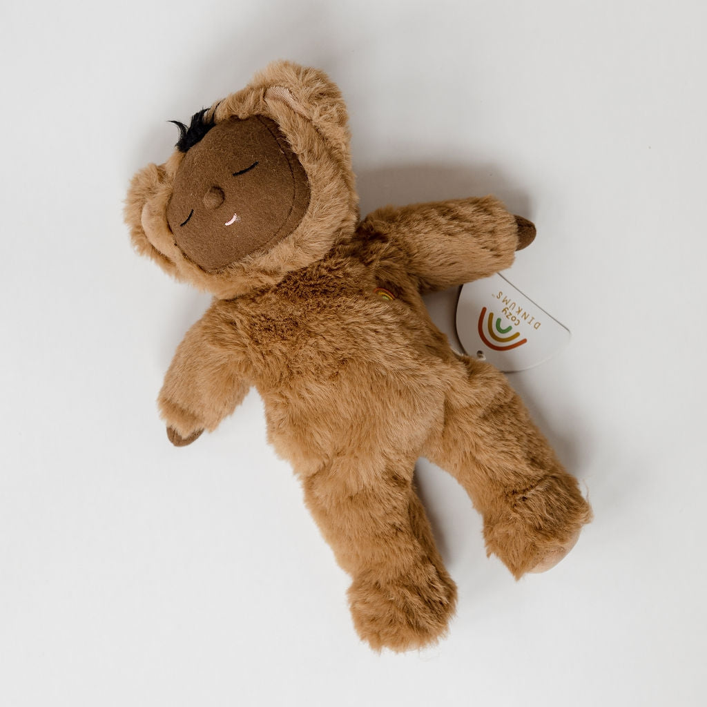 A cozy dinkums teddy mini by Olli Ella, laying on a white surface.