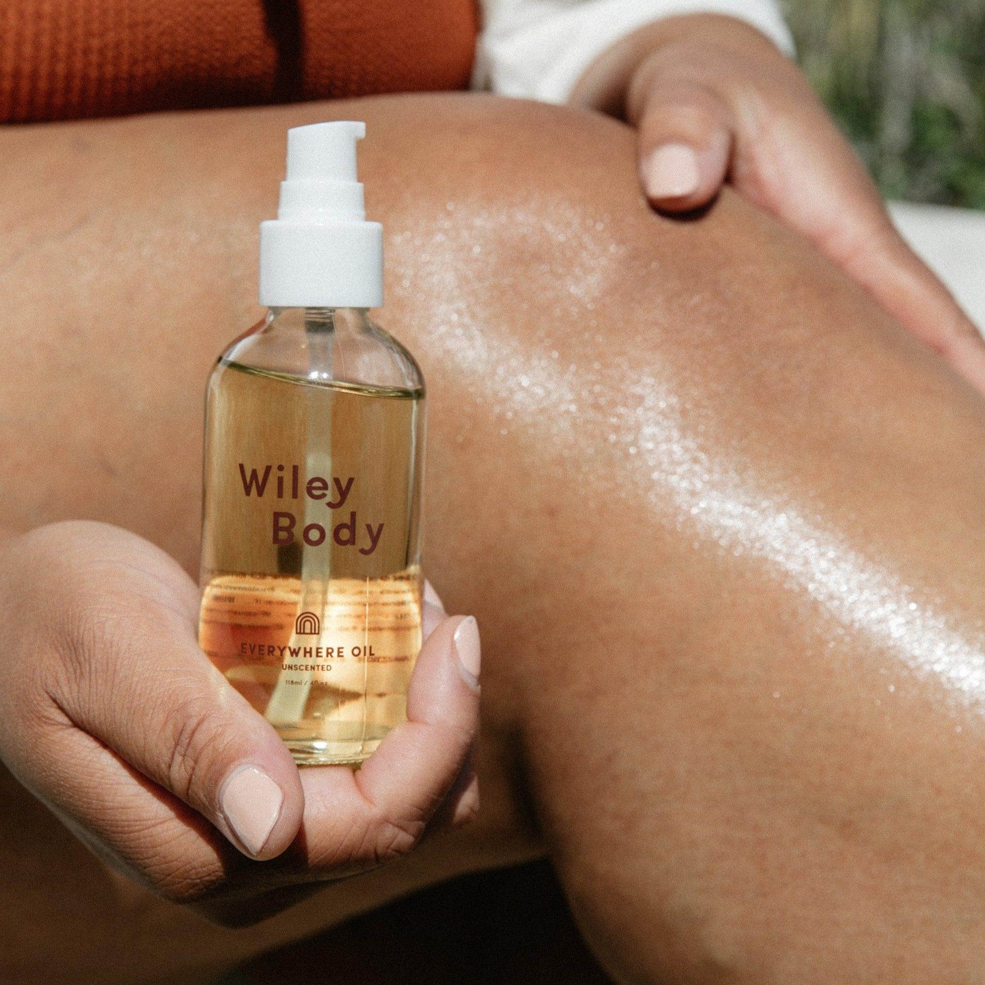 A woman holding a nourishing bottle of Wiley Body's everywhere oil.