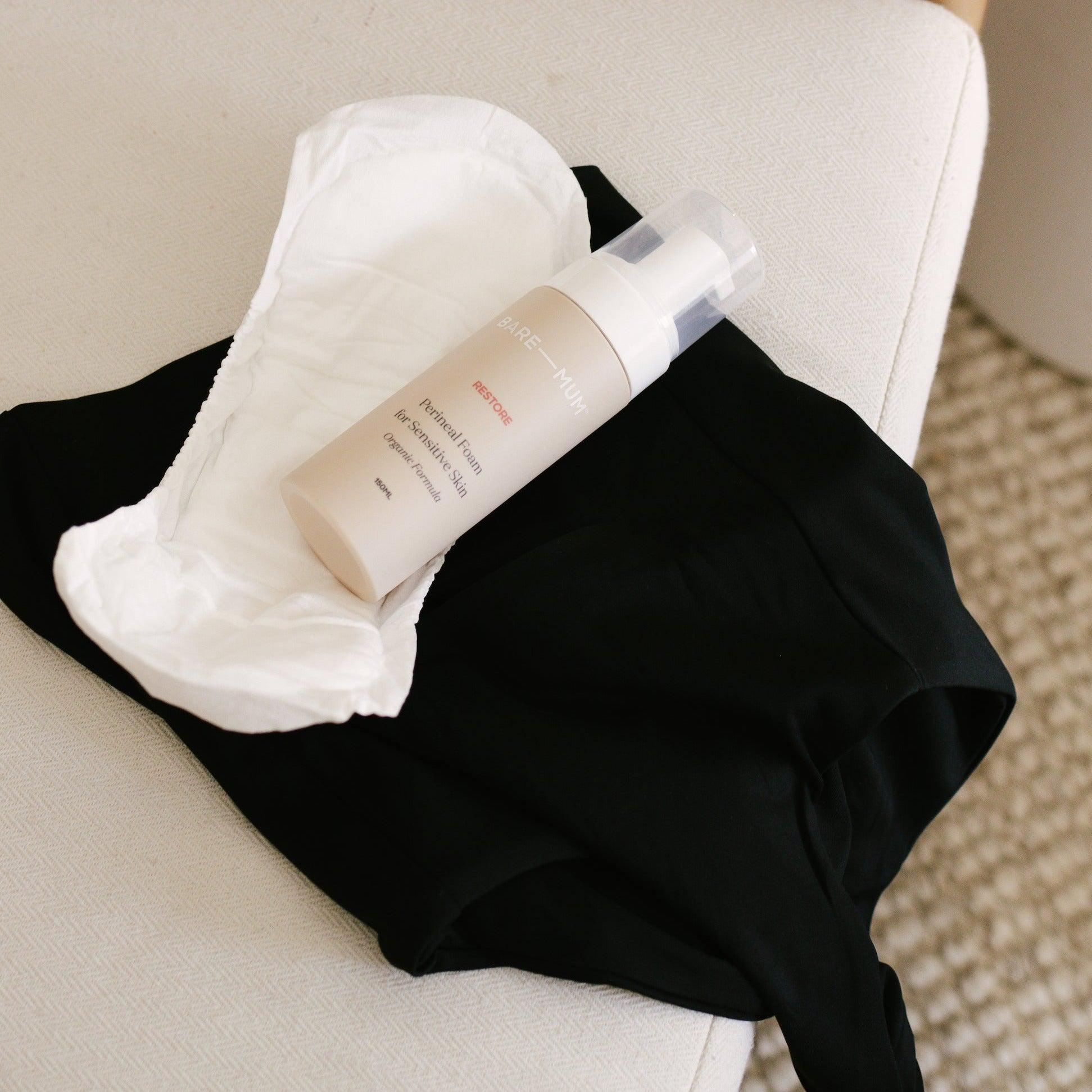 A pair of Postpartum Briefs by Bare Mum assisting in a mother's recovery after birth, carefully placed on top of a white couch.