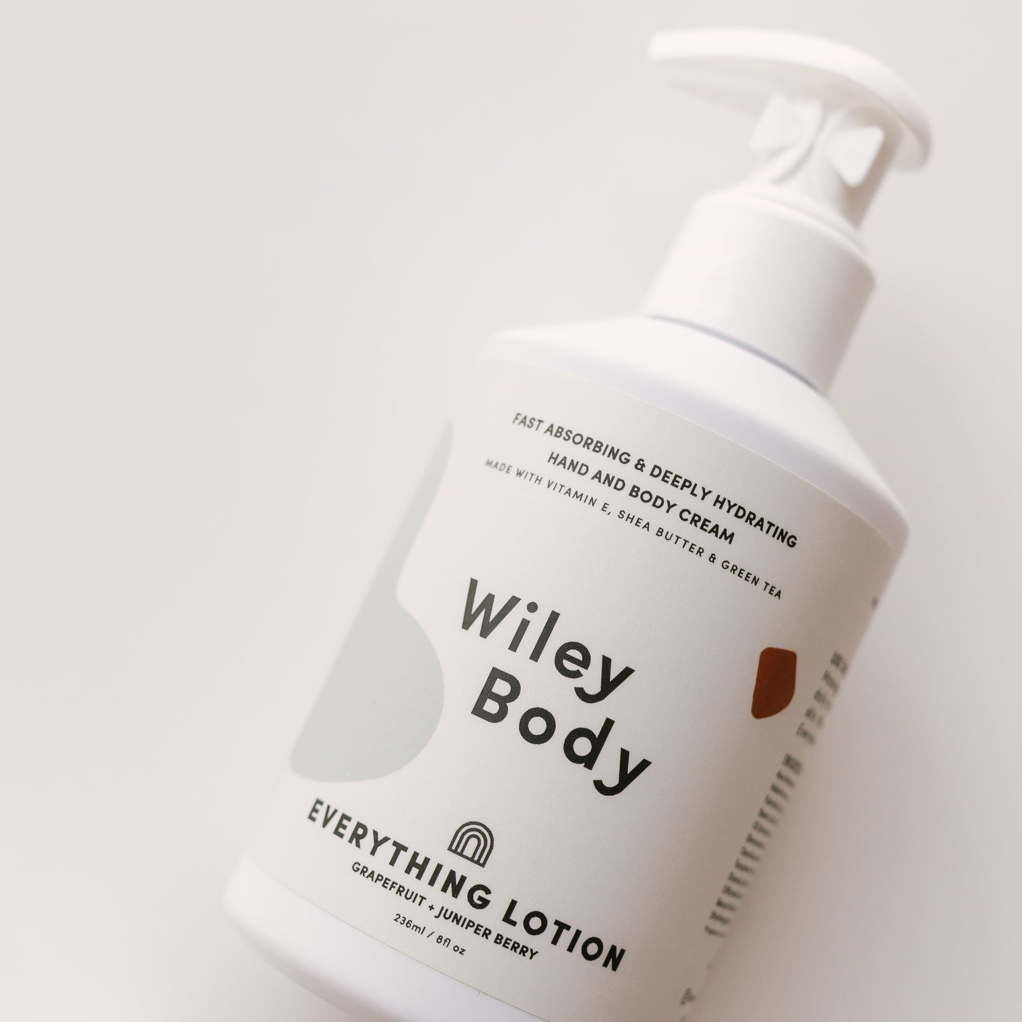 A bottle of Wiley Body's everything lotion on a white surface.
