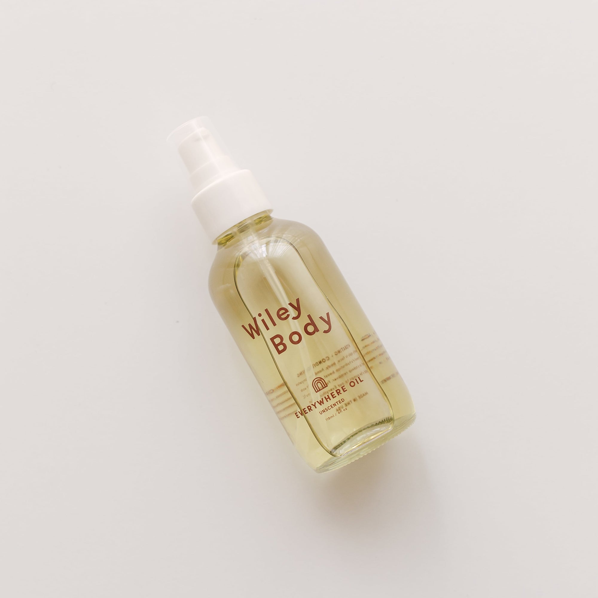 A nourishing bottle of Wiley Body everywhere oil on a white surface.