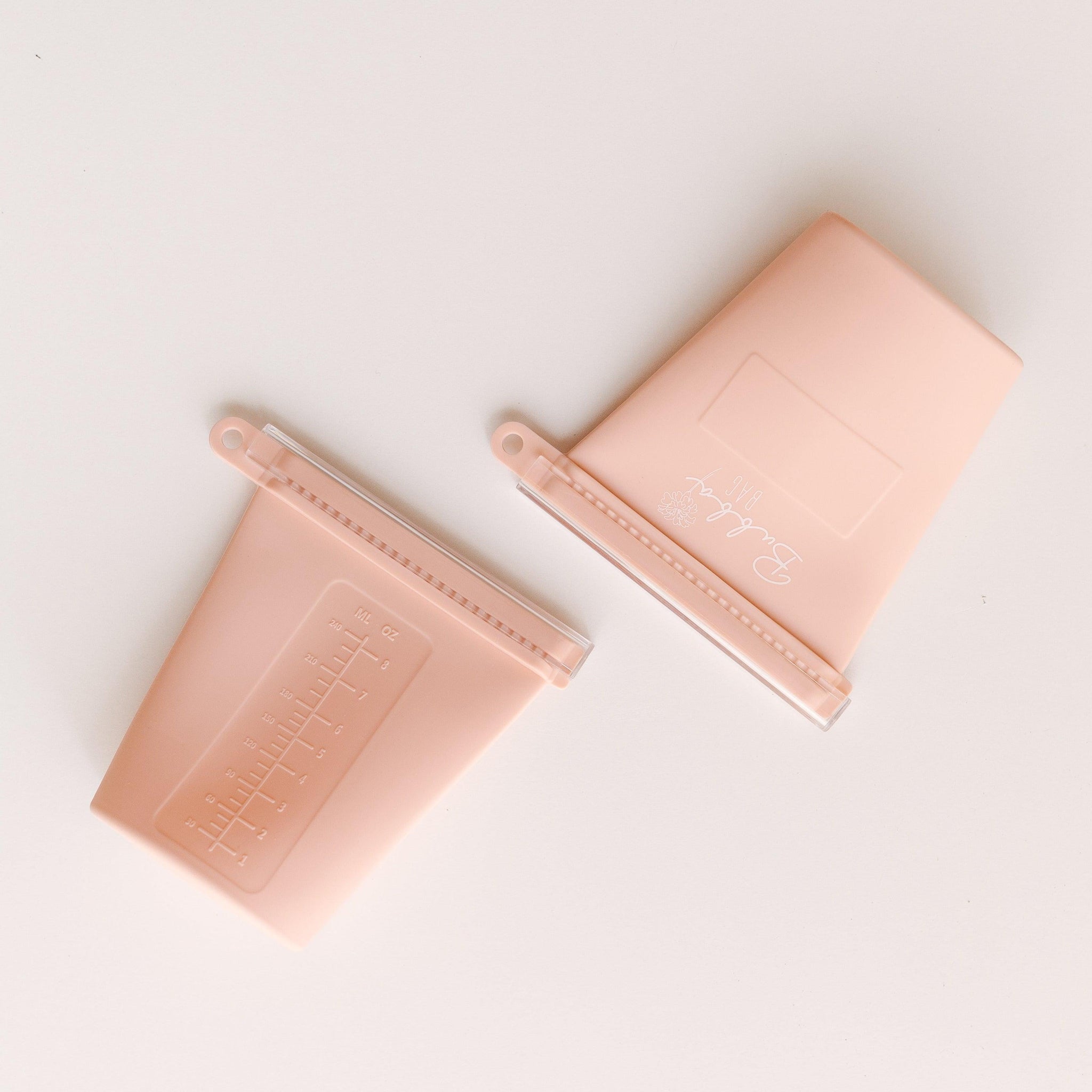 Two Marigold Baby pink plastic containers on a white surface.