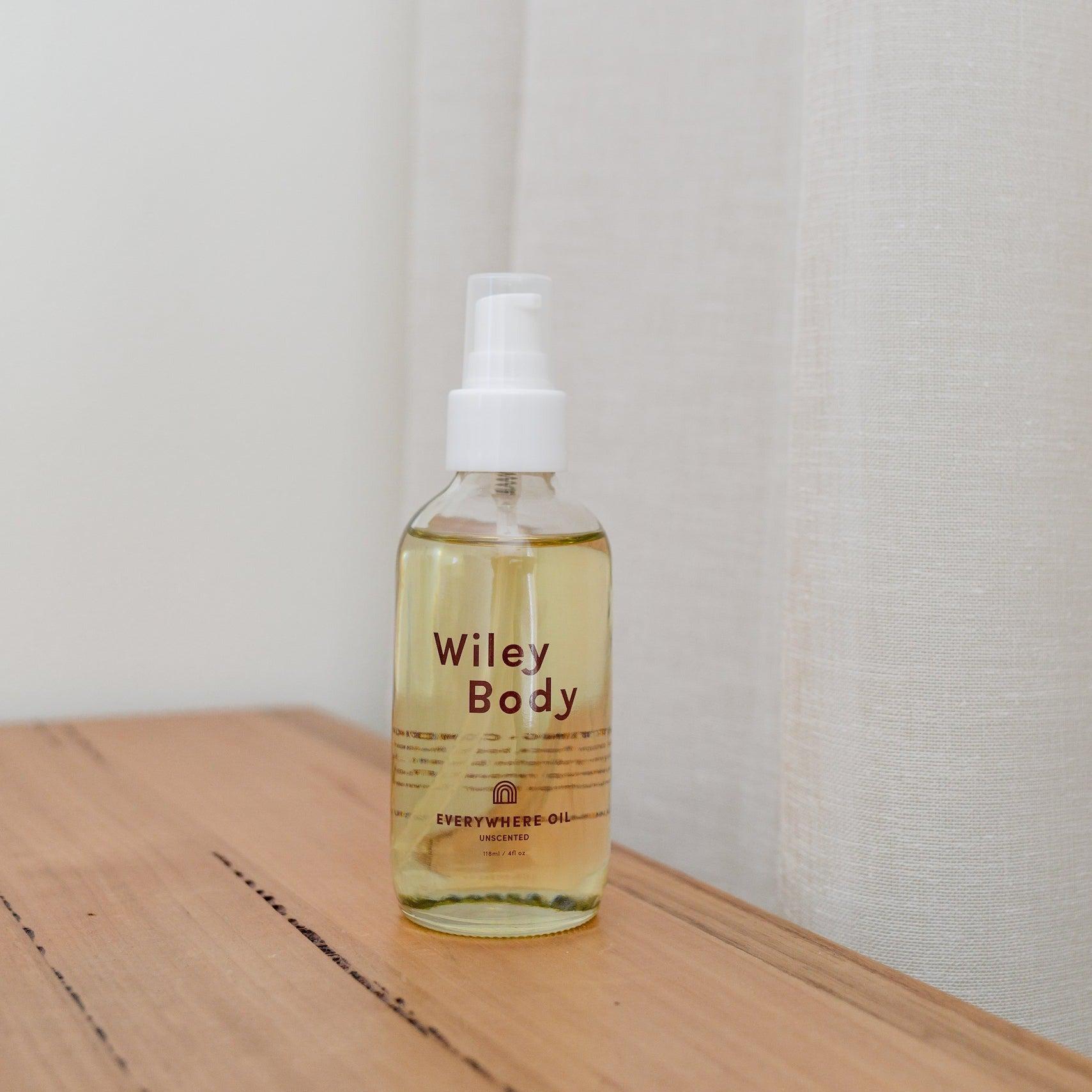 A nourishing bottle of Wiley Body everywhere oil sitting on a wooden table, ready to moisturize.