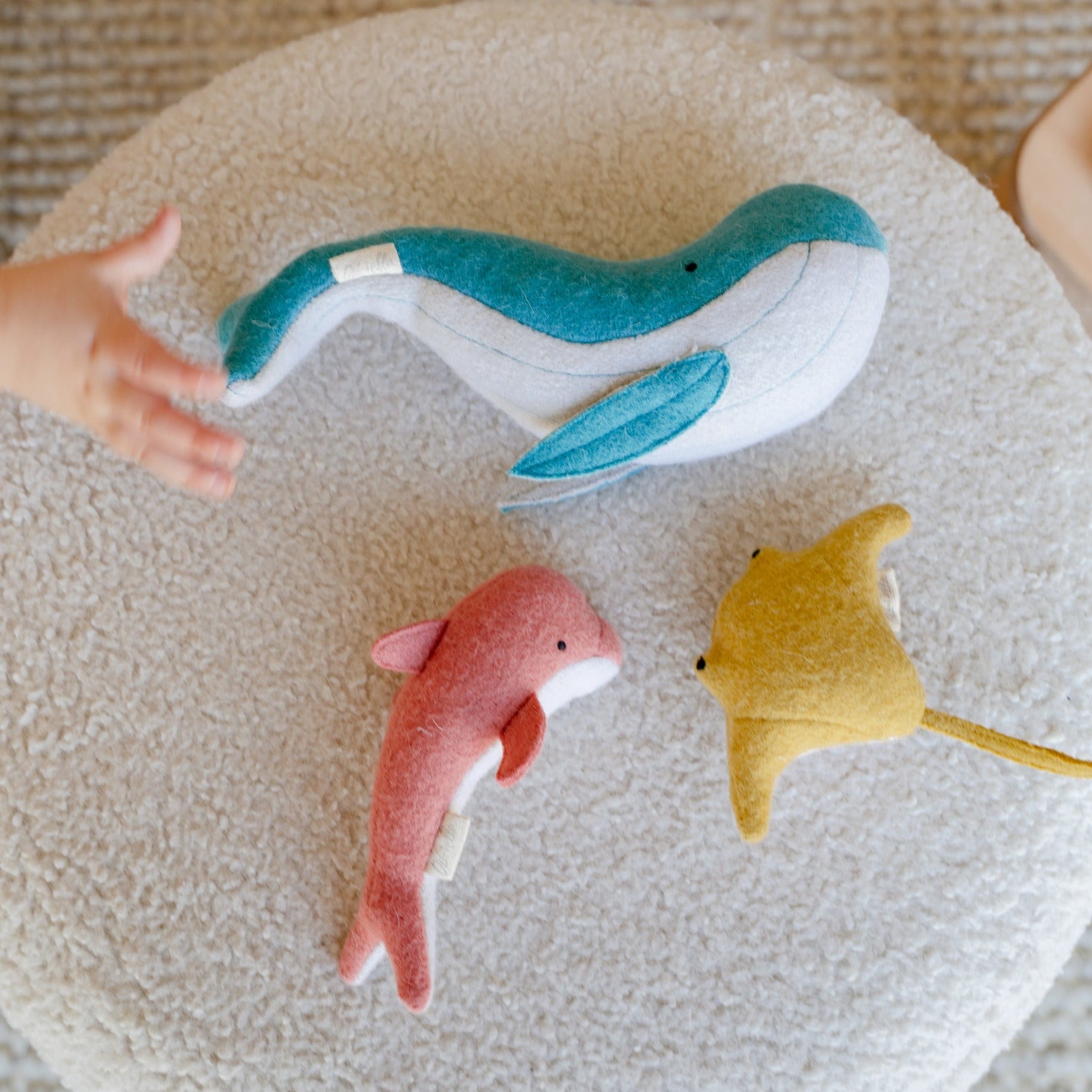 A child is engaging in imaginative play, reaching out to a Holdie Folk - Ocean Animals from Olli Ella in the ocean.