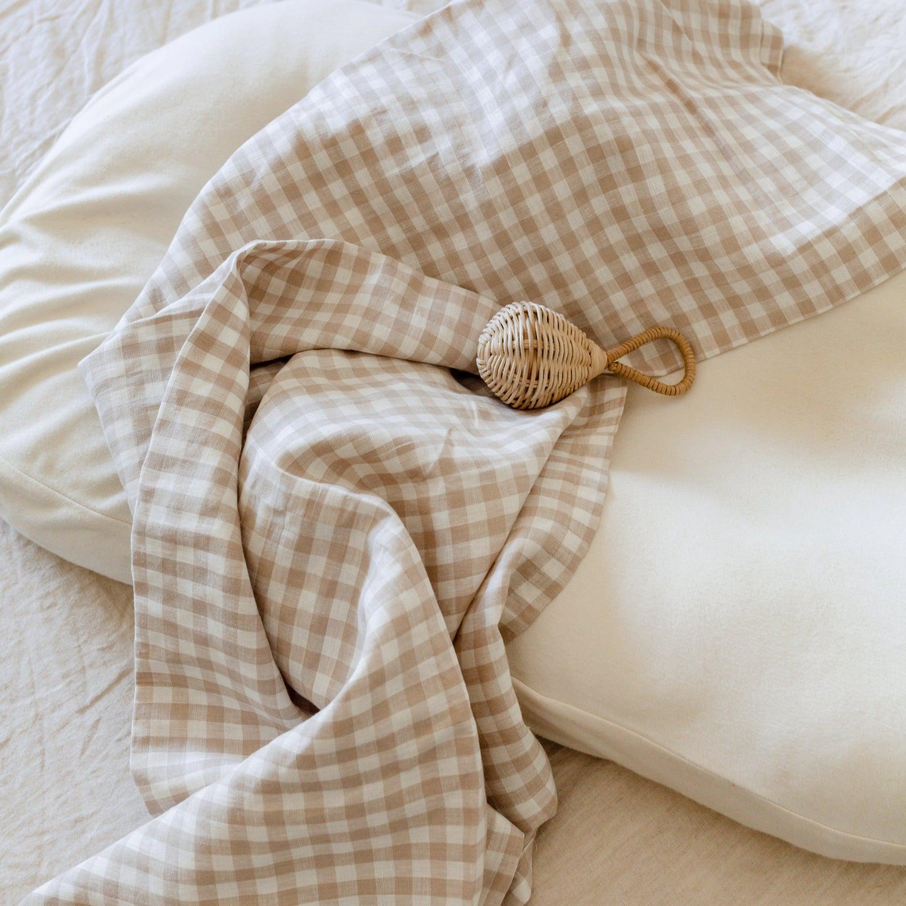 A white and beige checkered blanket, reminiscent of French linen styles, adorning a bed.
