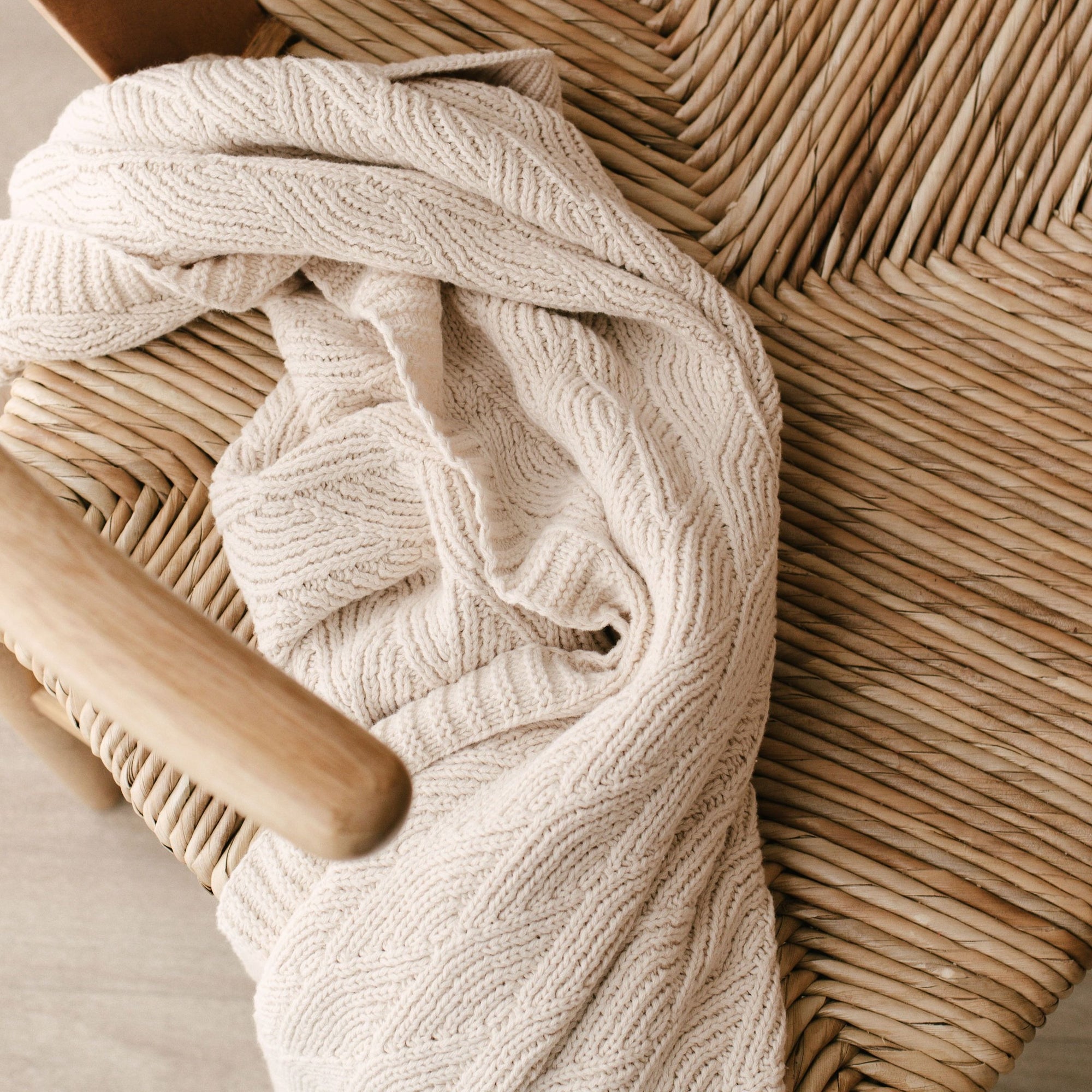 A Bundl. organic cotton blanket is sitting on a wooden chair.