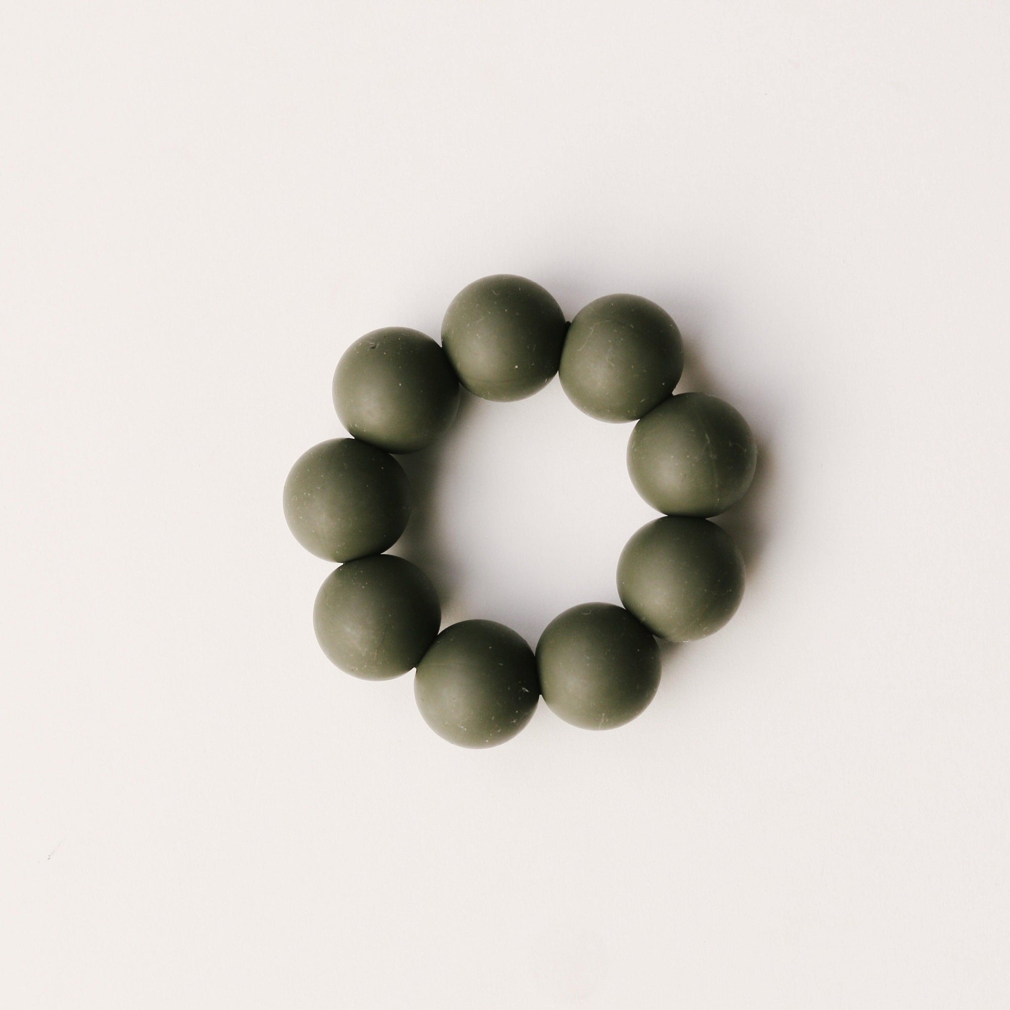 A Dove & Dovelet Silicone Teether in the shade Olive.