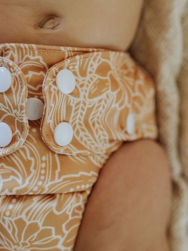 A close up of a baby wearing a modern cloth diaper with a native print from EcoNaps in the shade Desert Cactus.