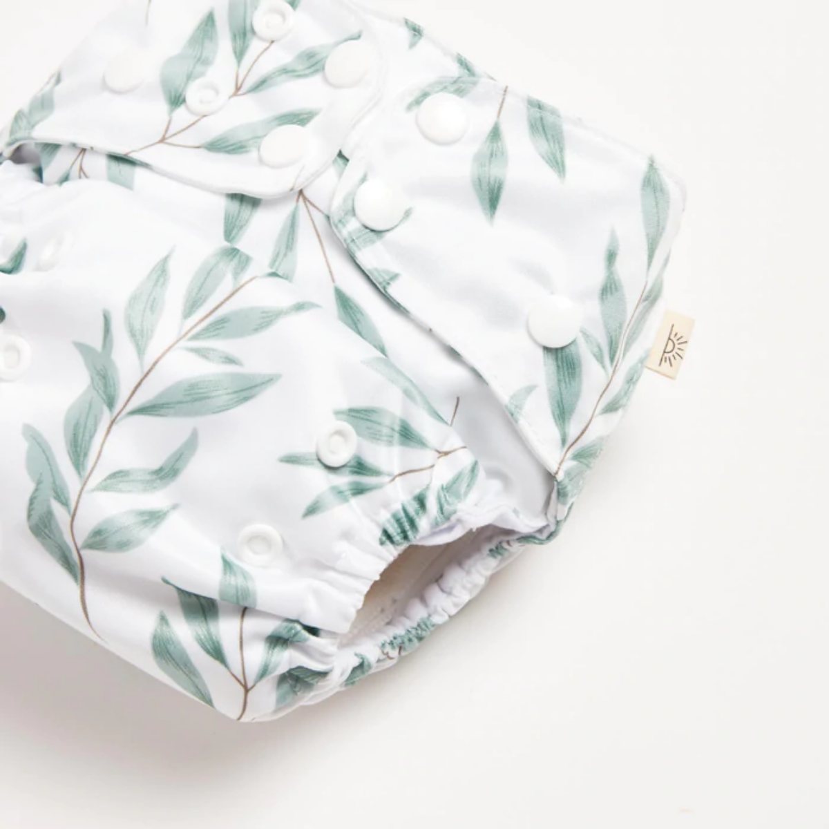A close up of Olive Leaf 2.0 Modern Cloth Nappy with green olive leaves on it by EcoNaps on a white surface.