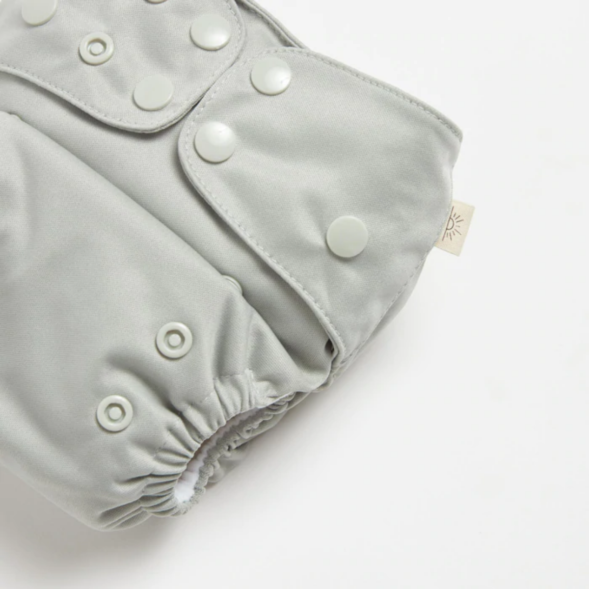 A close up of EcoNaps Sea Mist 2.0 modern cloth nappy, displayed on a white surface.