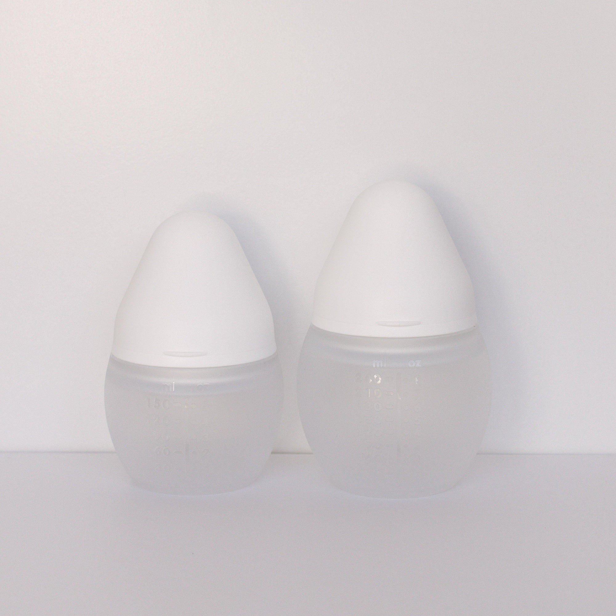 Two milk BibRond bottles by Elhée France standing against a white surface.