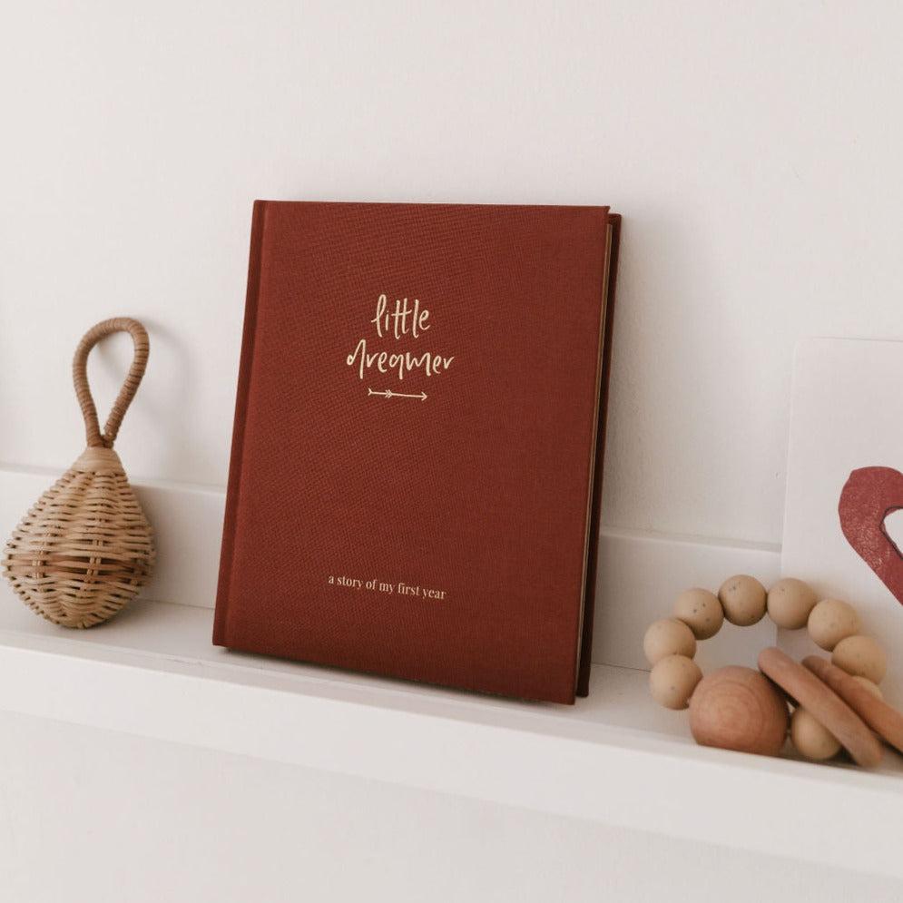 A little dreamer journal in pecan by Emma Kate Co on a shelf next to a wooden toy. 