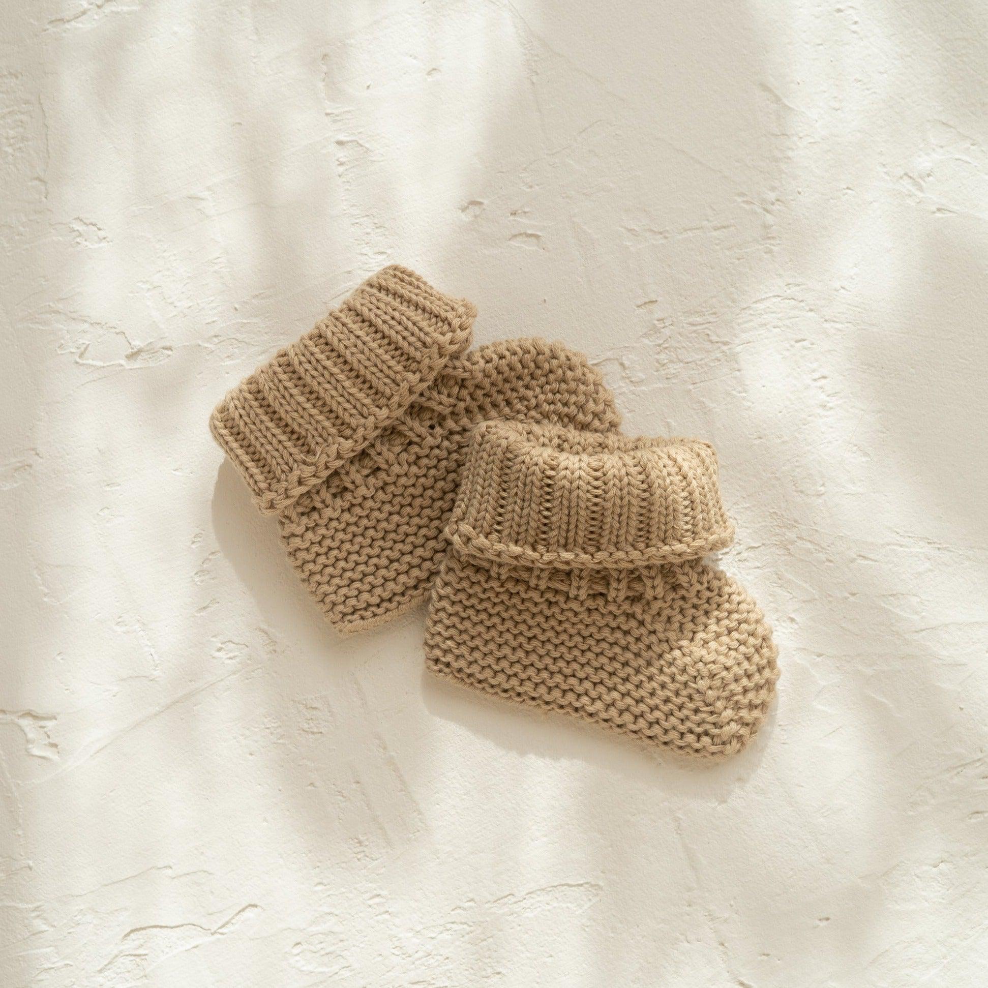 A pair of Illoura the Label organic cotton illoura baby booties in the color olive on a white surface.