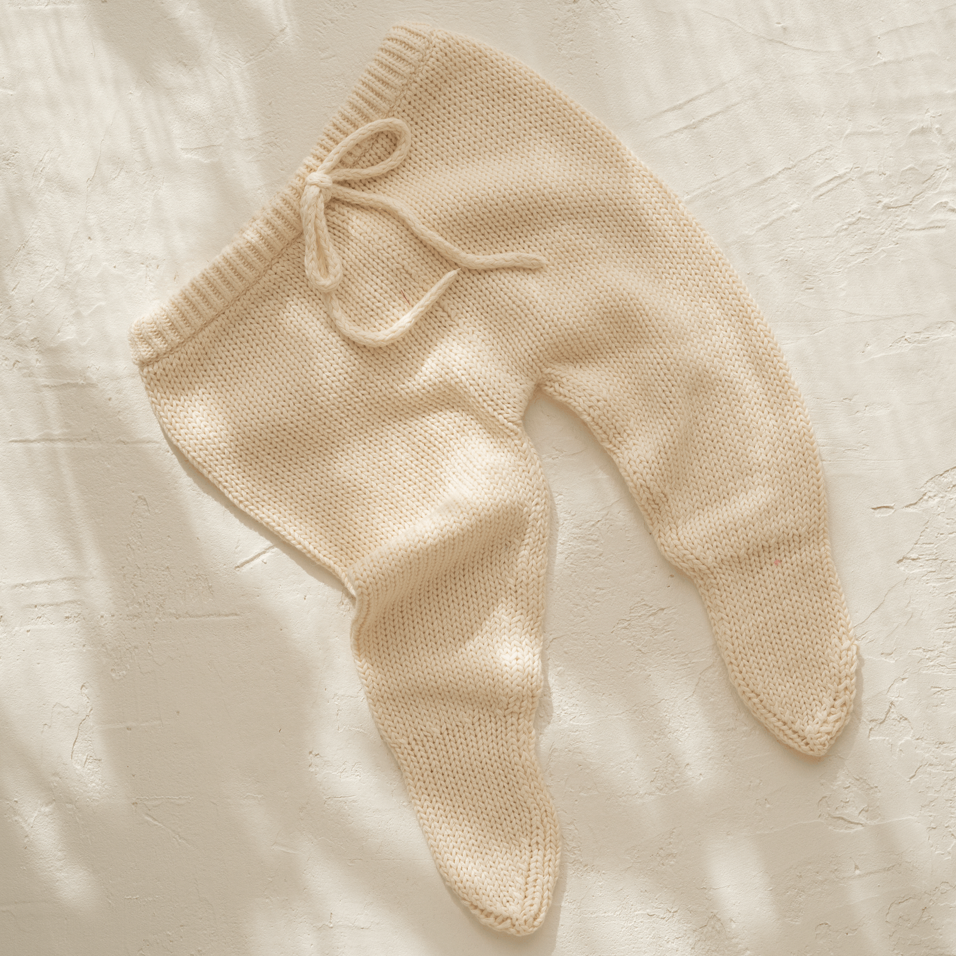 A baby's illoura poet pants in vanilla, from Illoura the Label, laying on a white surface.