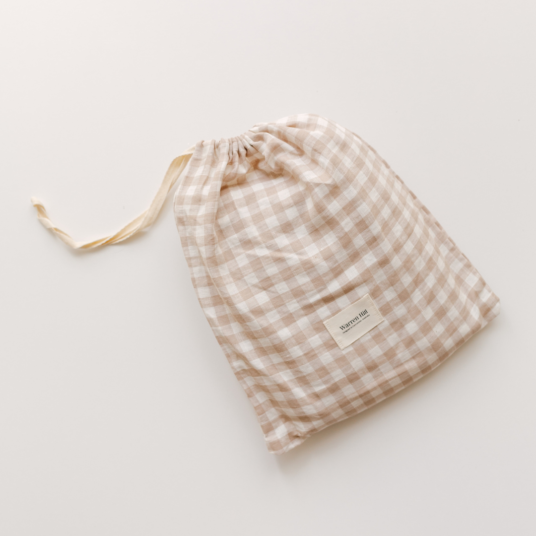 A beige and white checkered Warren Hill drawstring bag on a white surface, perfect for a neutral nursery.