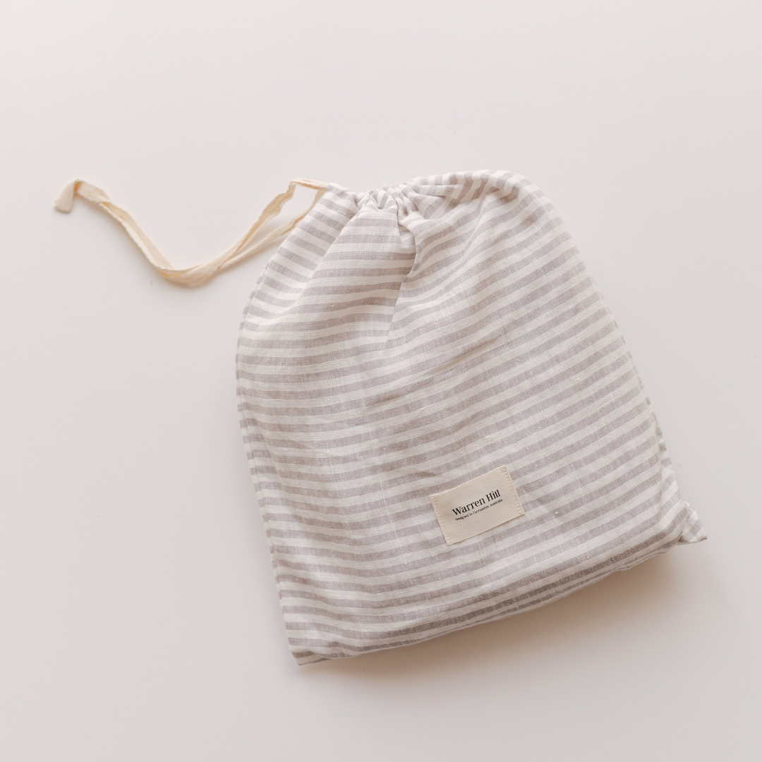 A Warren Hill french linen fitted cot sheet | grey stripe on a white surface.