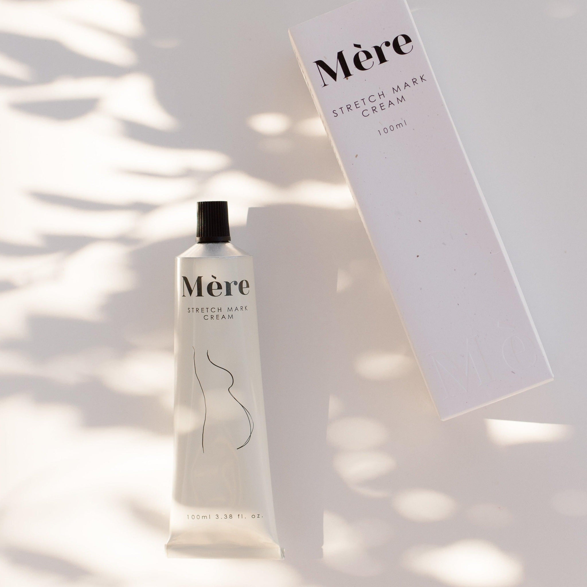 A tube of Mère stretch mark cream on a white surface next to its box.