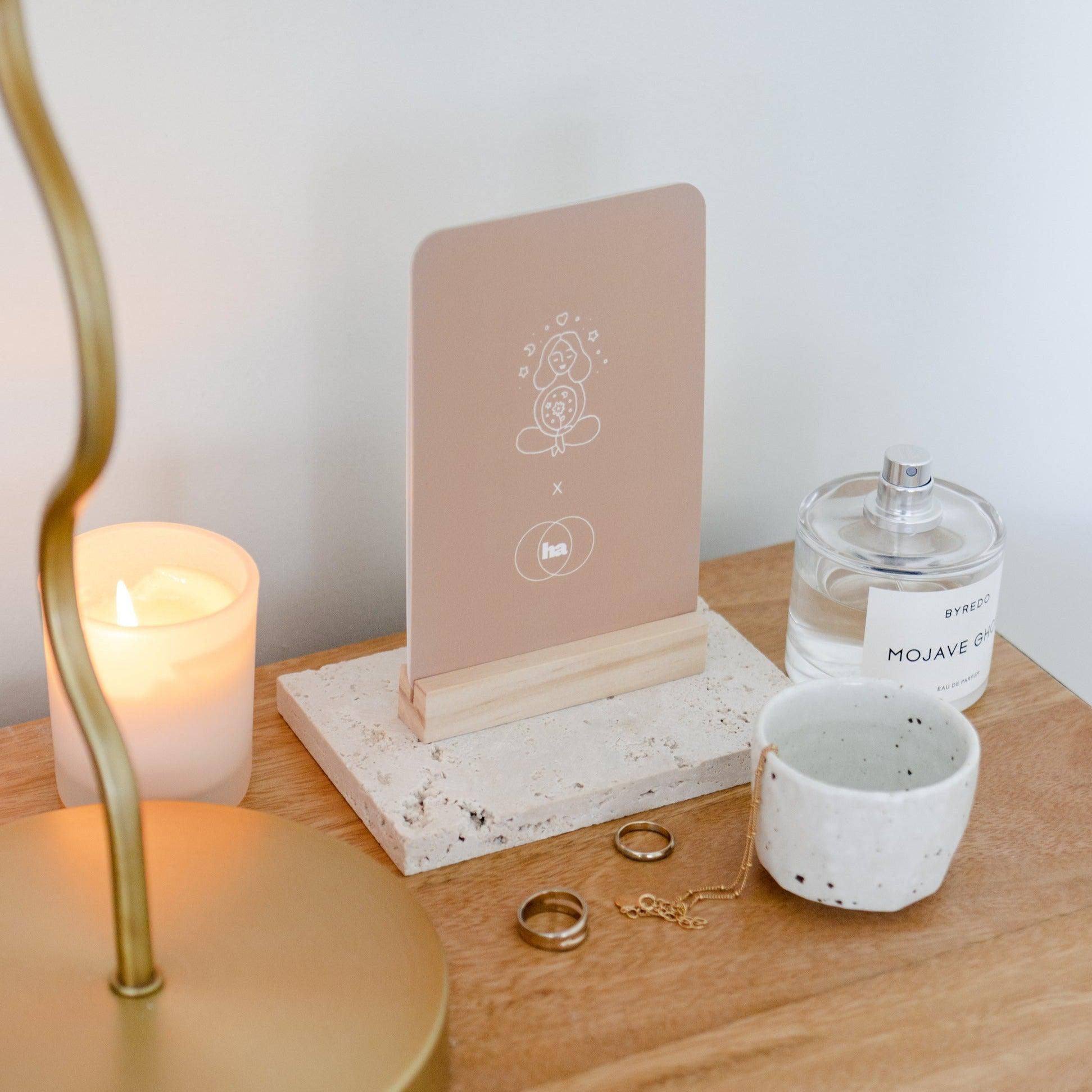 A bedside table adorned with Seasons of Mama affirmation cards and candles.