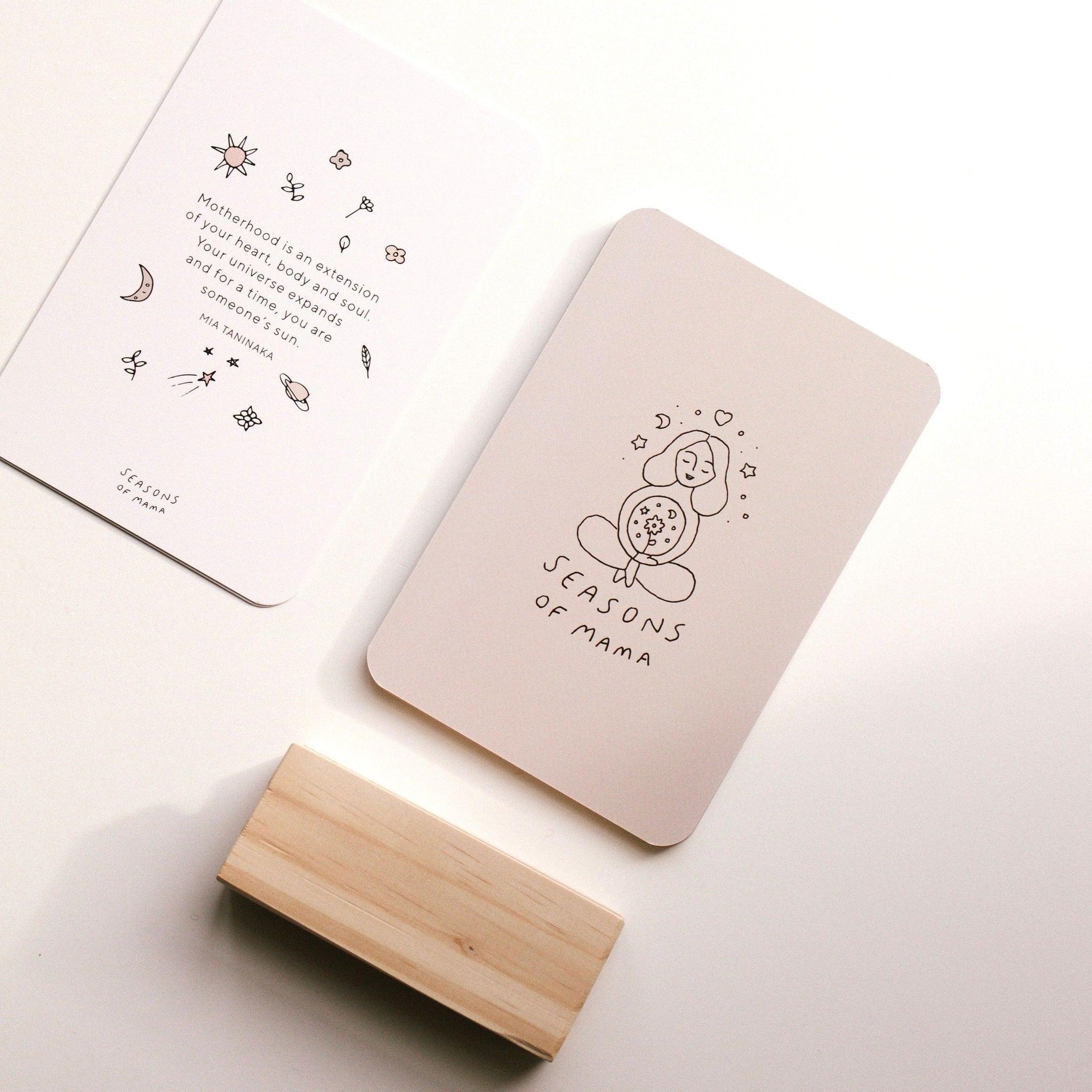 A set of Mama Mantra Cards and a wooden block on a table from Seasons of Mama, featuring motherhood quotes and affirmation cards.