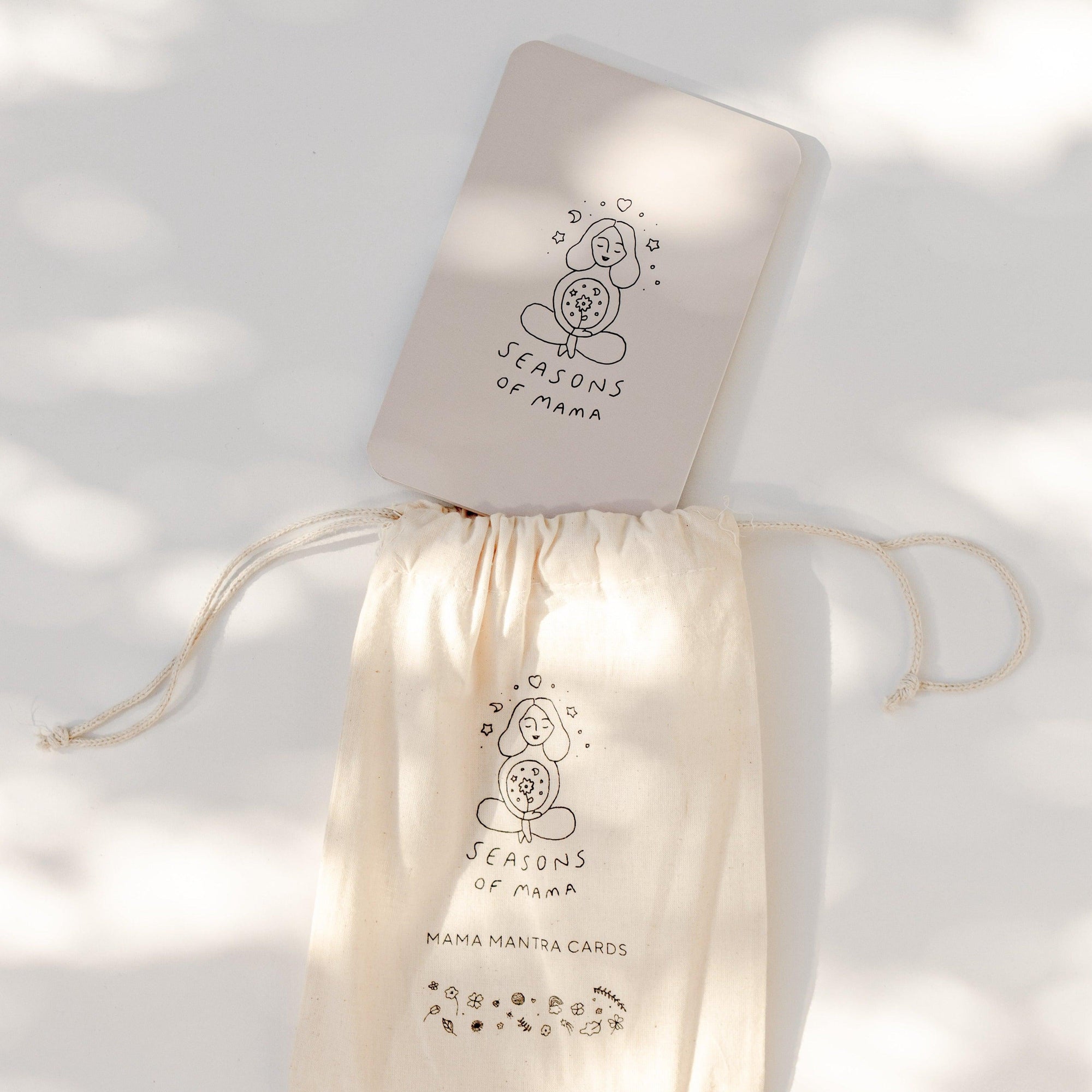 A branded calico bag with the Mama Mantra Cards by Seasons of Mama, featuring mother card quotes.