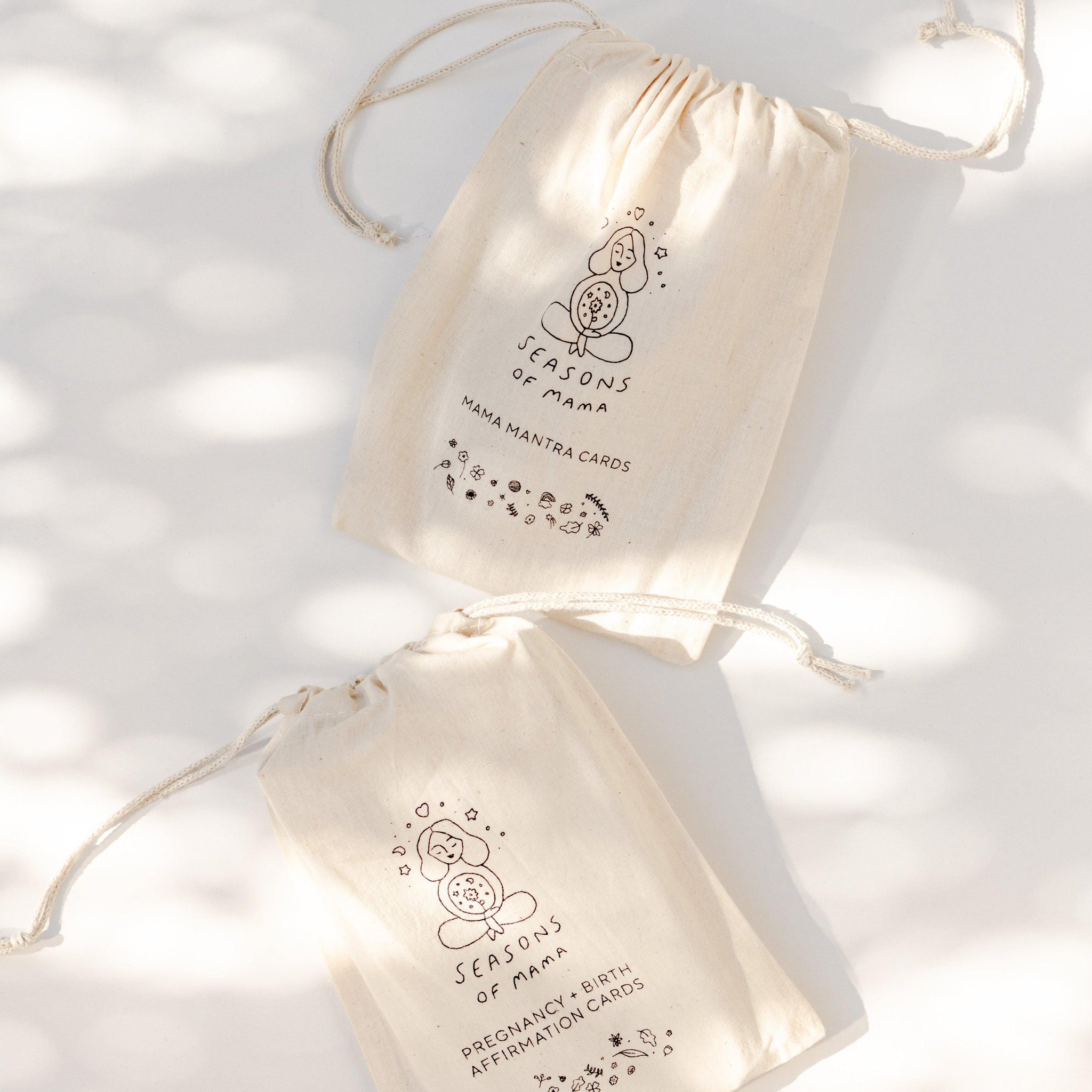 Two branded calico bags featuring Mama Mantra Cards and Pregnancy and Birth Affirmation Cards from Seasons of Mama.