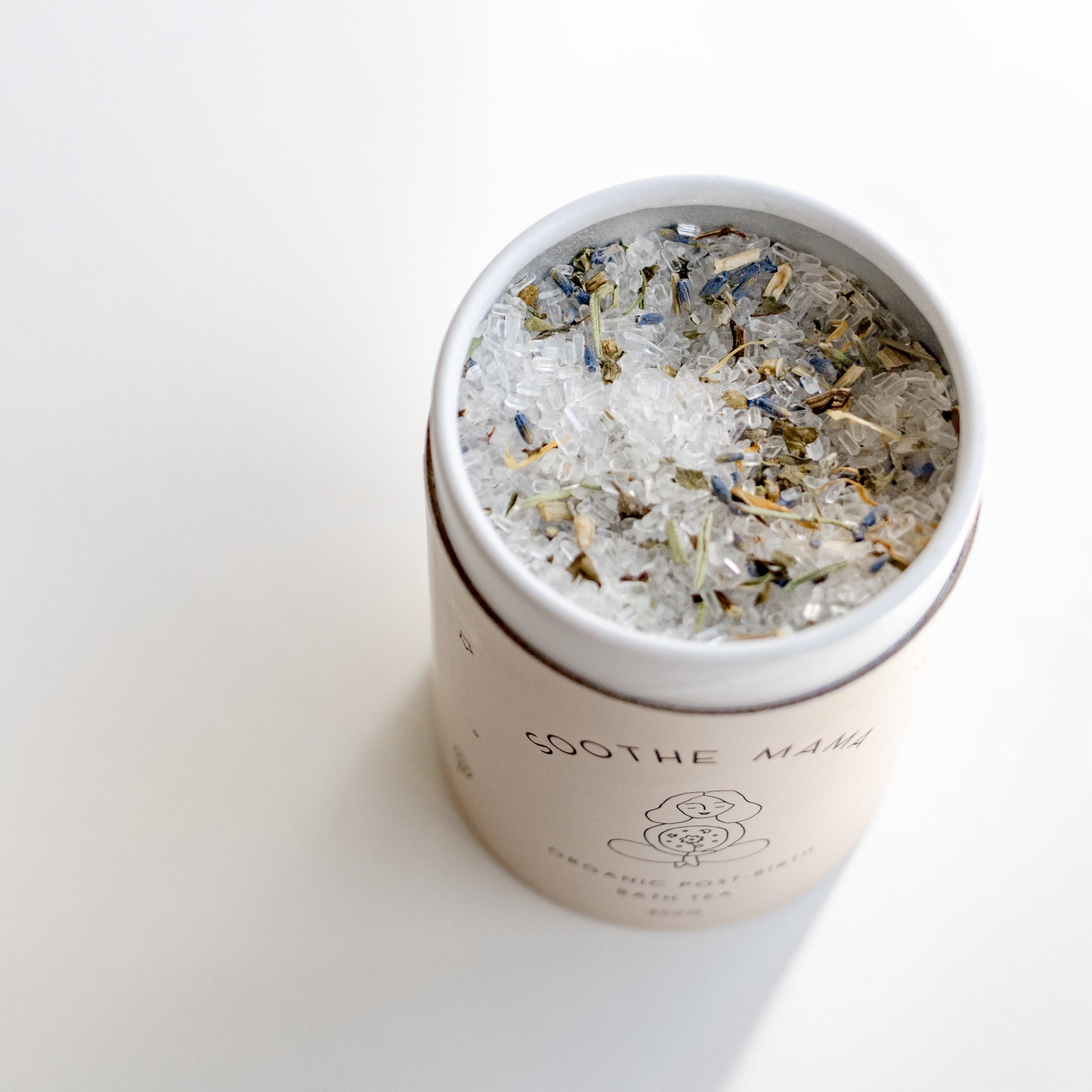 A tin of Seasons of Mama Soothe Mama Organic Post-Birth Bath Tea., resting on a white surface.