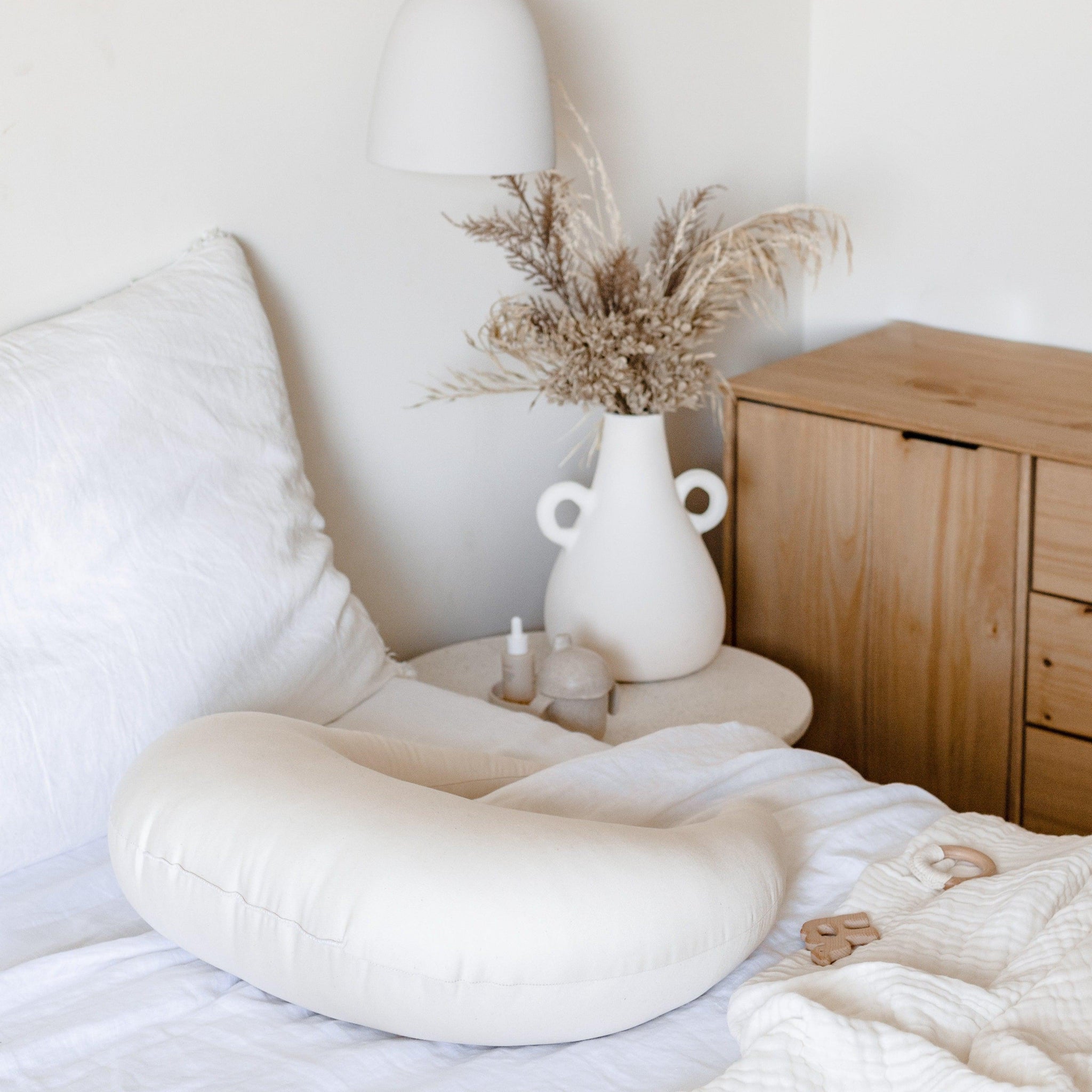 A white bed with a PREORDER Feeding & Support Pillow | Natural by Snuggle Me on it, perfect for snuggling and feeding.