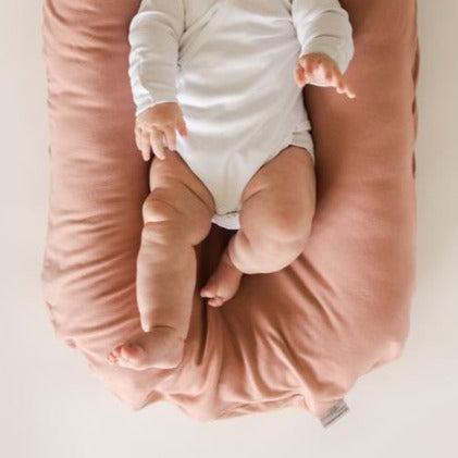 A baby is snuggled on a Snuggle Me Lounger with the Snuggle Me Lounger Cover in Gumdrop.