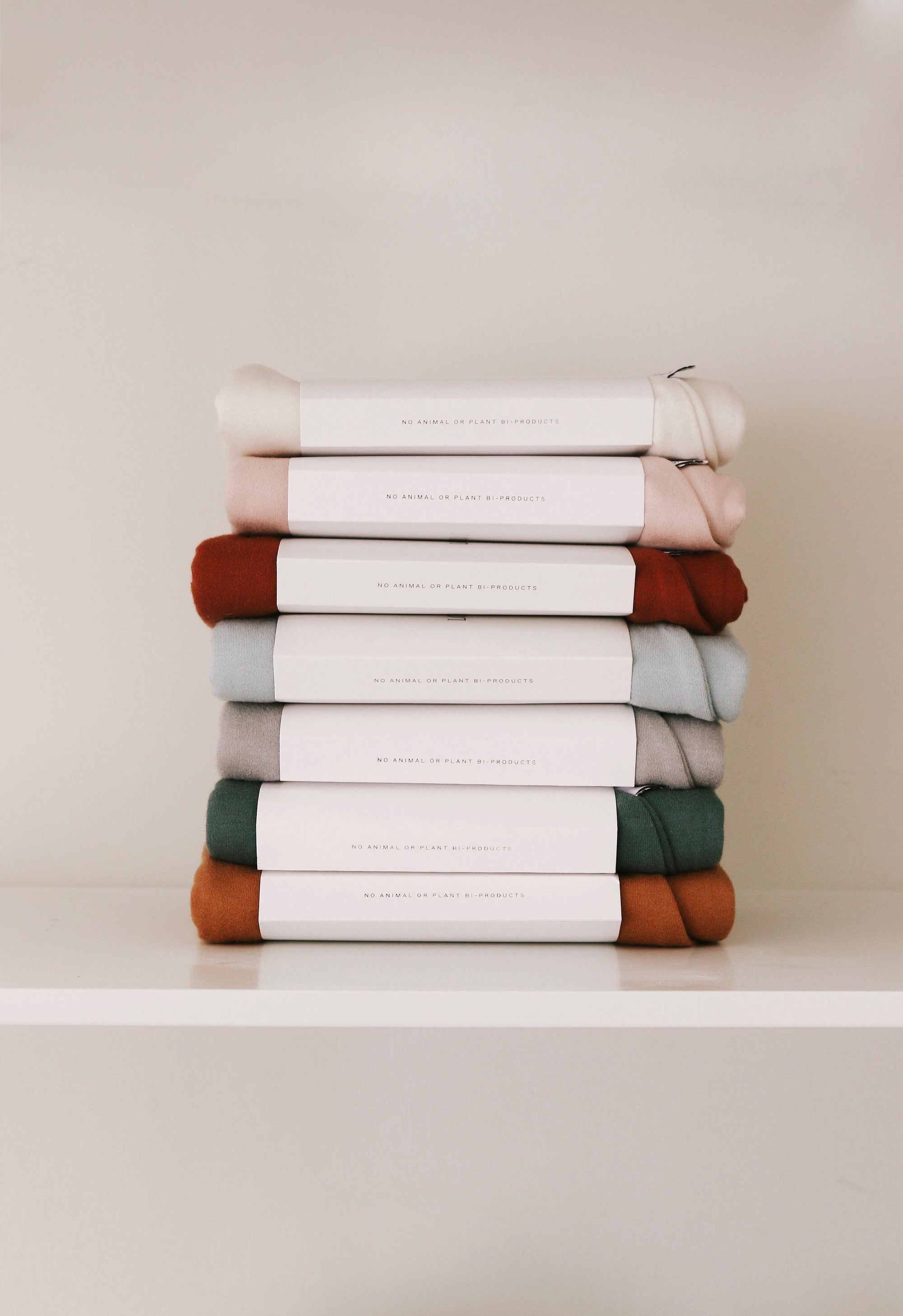 A stack of Snuggle Me Lounger Covers | Natural on a white shelf.